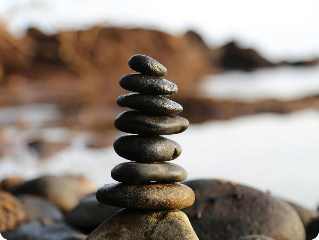 Balanced rocks near water representing the PEACE Method mom weight loss program