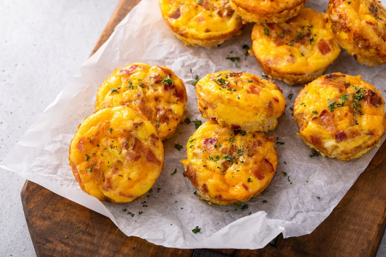 High-protein egg muffin cups made with eggs, cheese, and veggies, shown on parchment paper. A portable, travel-friendly breakfast idea for busy women who need quick, balanced morning meals.