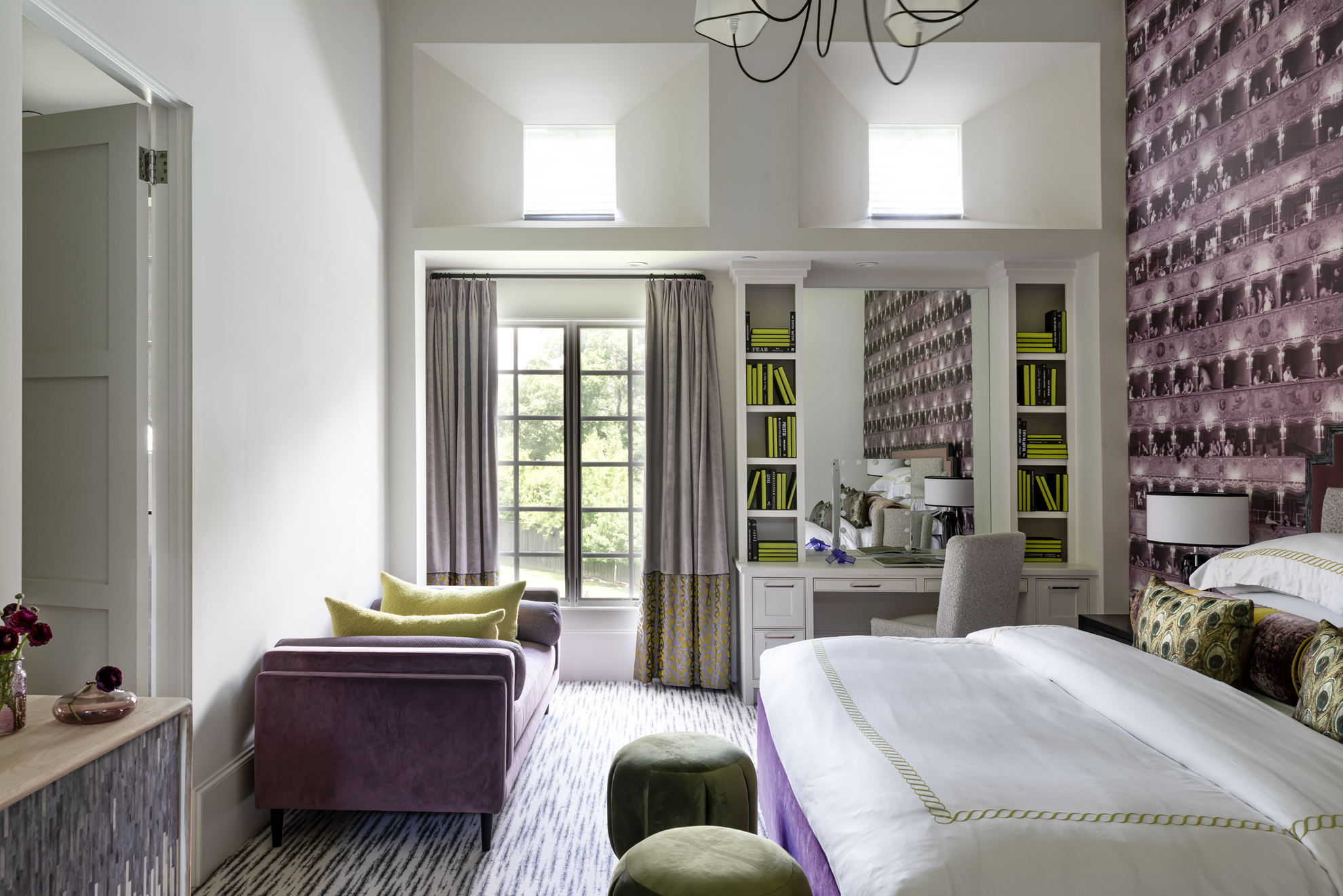 French country home in Houston guest bedroom with a purple sofa, built-in desk, window seat and patterned wall covering.