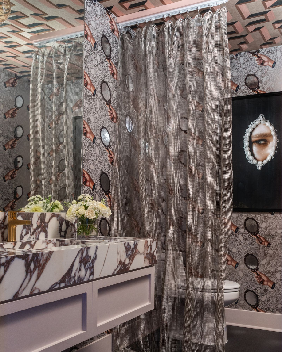 Wellness clinic Houston bathroom with a metal mesh curtain, veined marble vanity and playful mirror-pattern wallpaper.