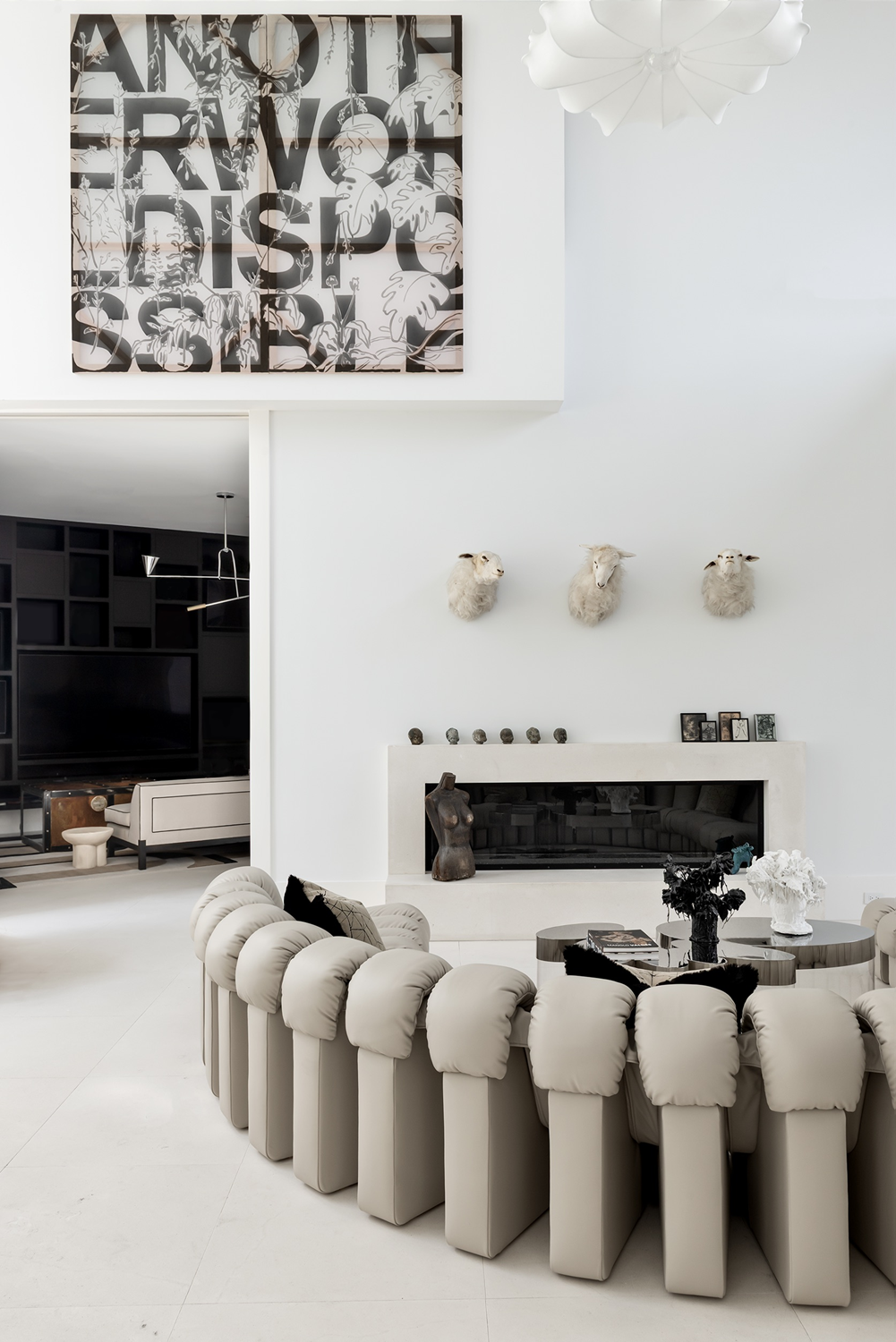 Modern luxury home in Houston living room with a curved De Sede sofa, fireplace, contemporary art and sculptural decor.