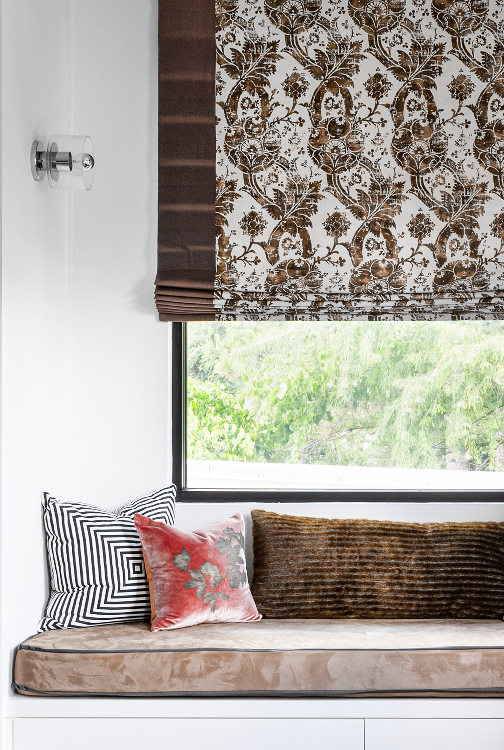 Modern luxury home in Houston guest bedroom window seat with graphic cushions and a patterned brown Roman shade.