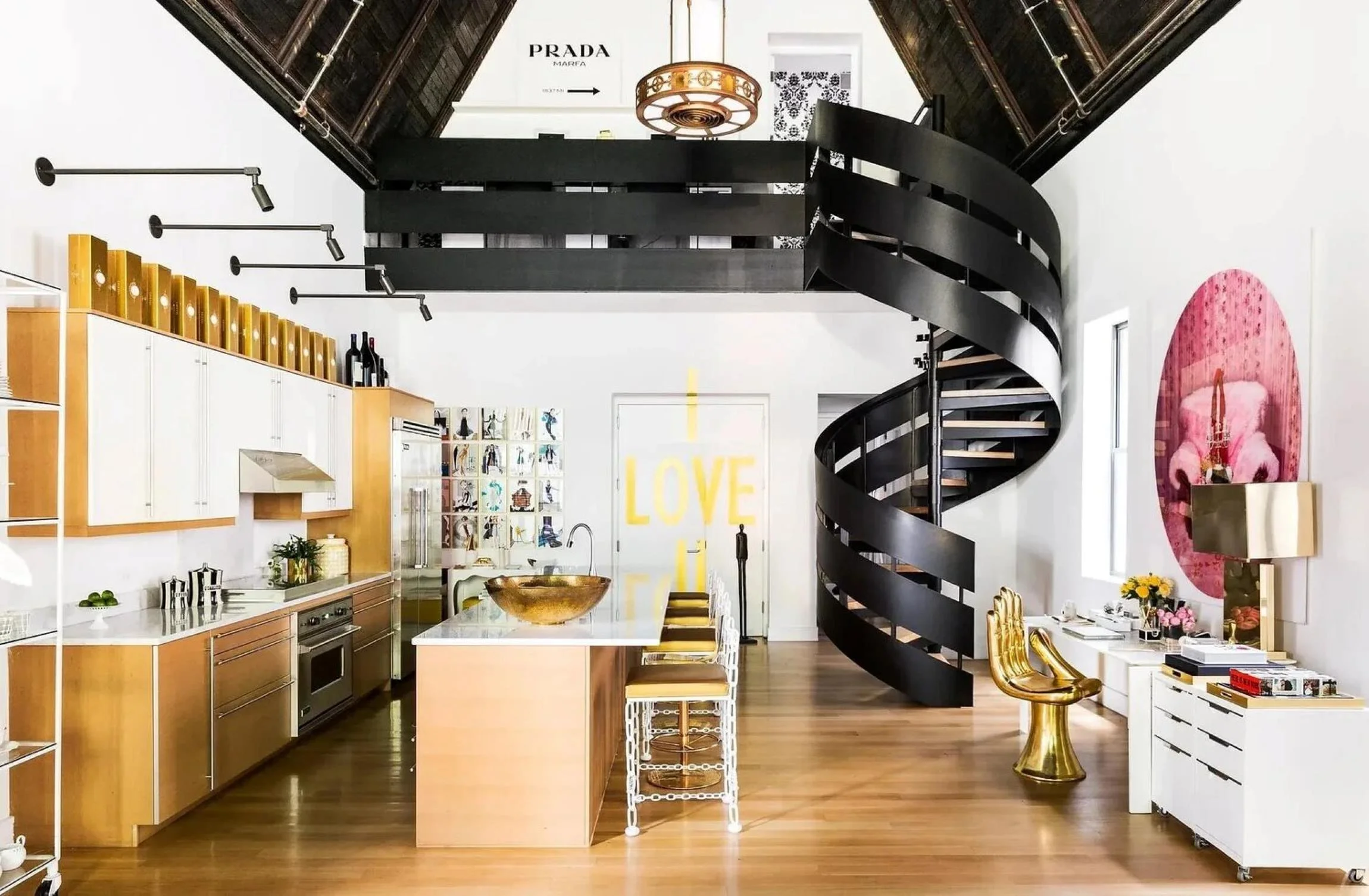 Clapton Chapel apartment kitchen with gold cabinetry, a black spiral staircase, vaulted ceiling and statement artwork.