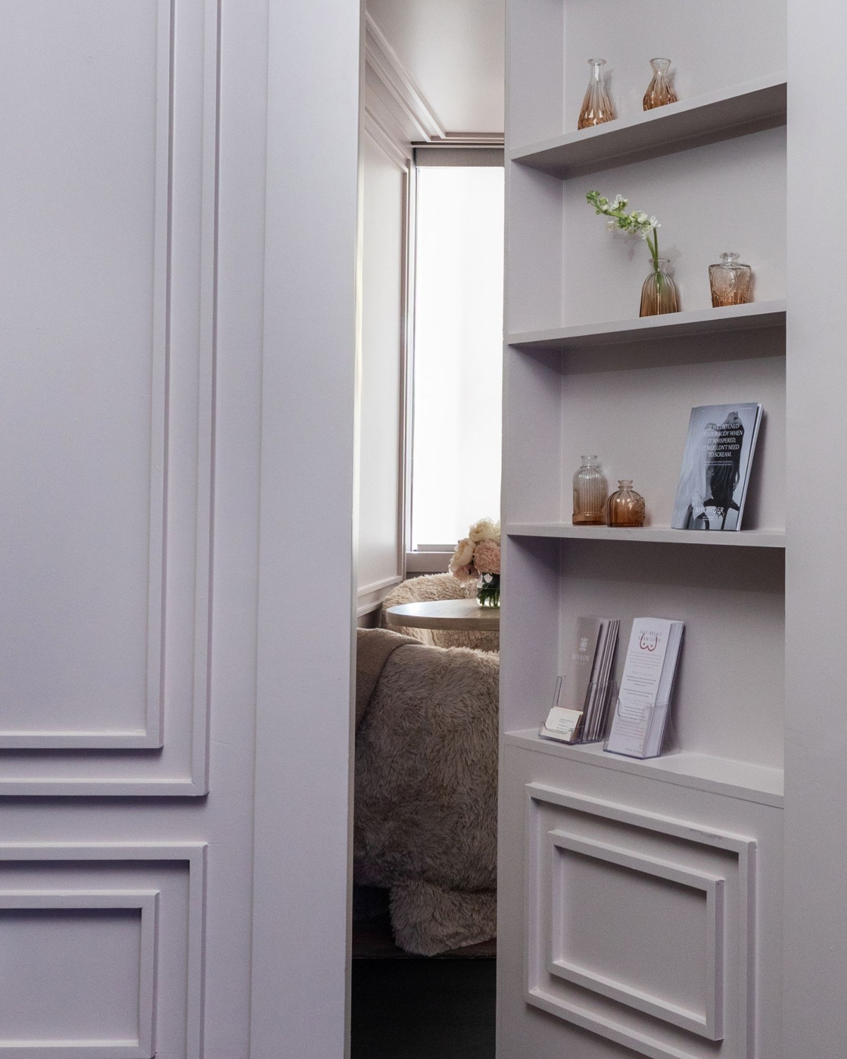 Wellness clinic Houston interior with pale built-in shelving, panelled walls and a glimpse of a plush seating area.