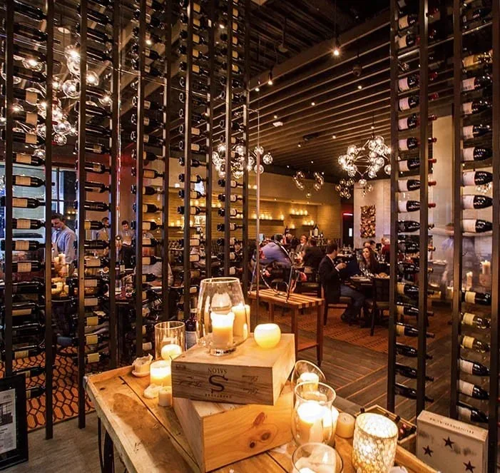 Restaurant interior design in Houston with wine display walls, warm ambient lighting and an upscale hospitality atmosphere