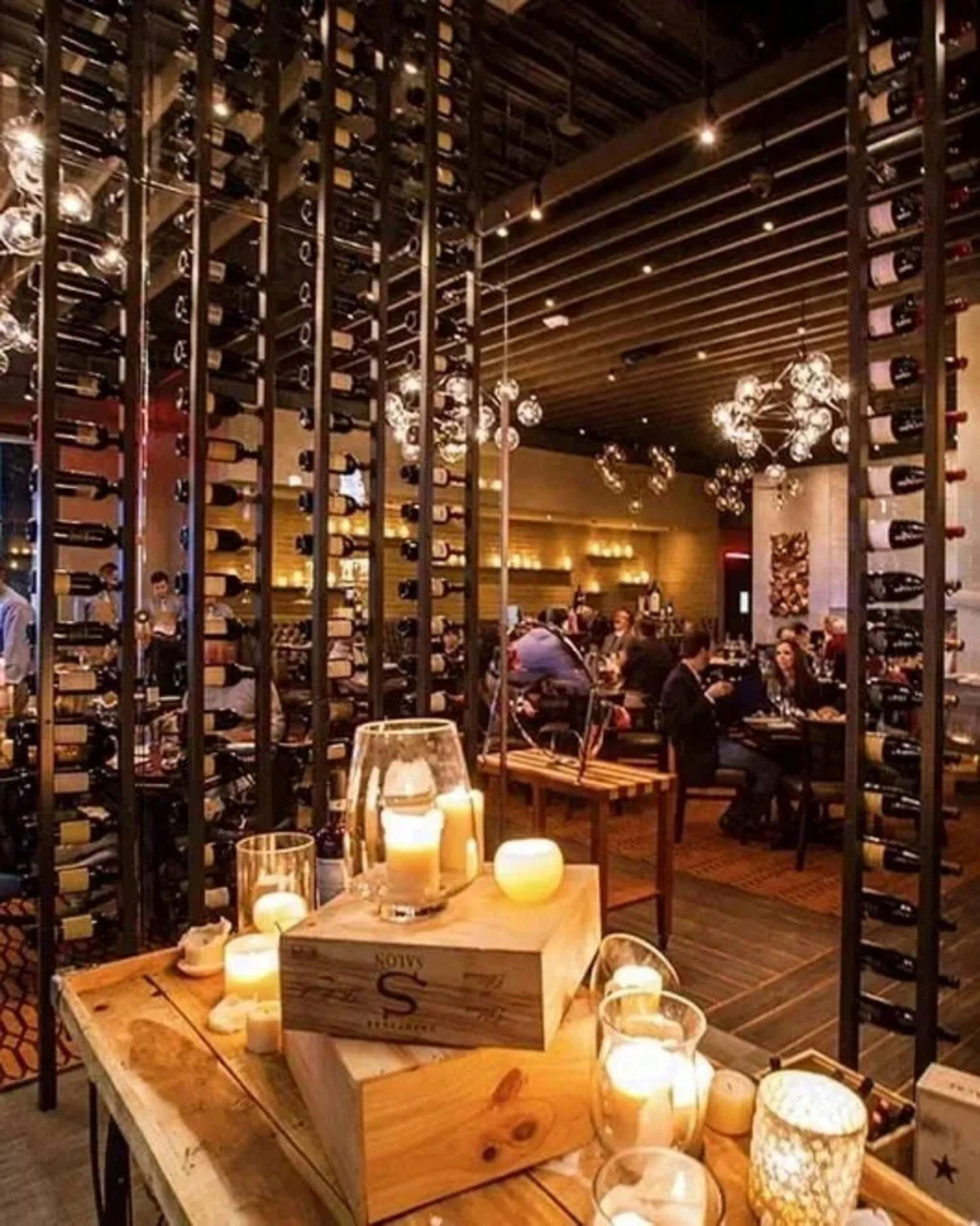 Vallone’s restaurant wine room with floor-to-ceiling bottle displays, candlelit tables and sculptural lighting.