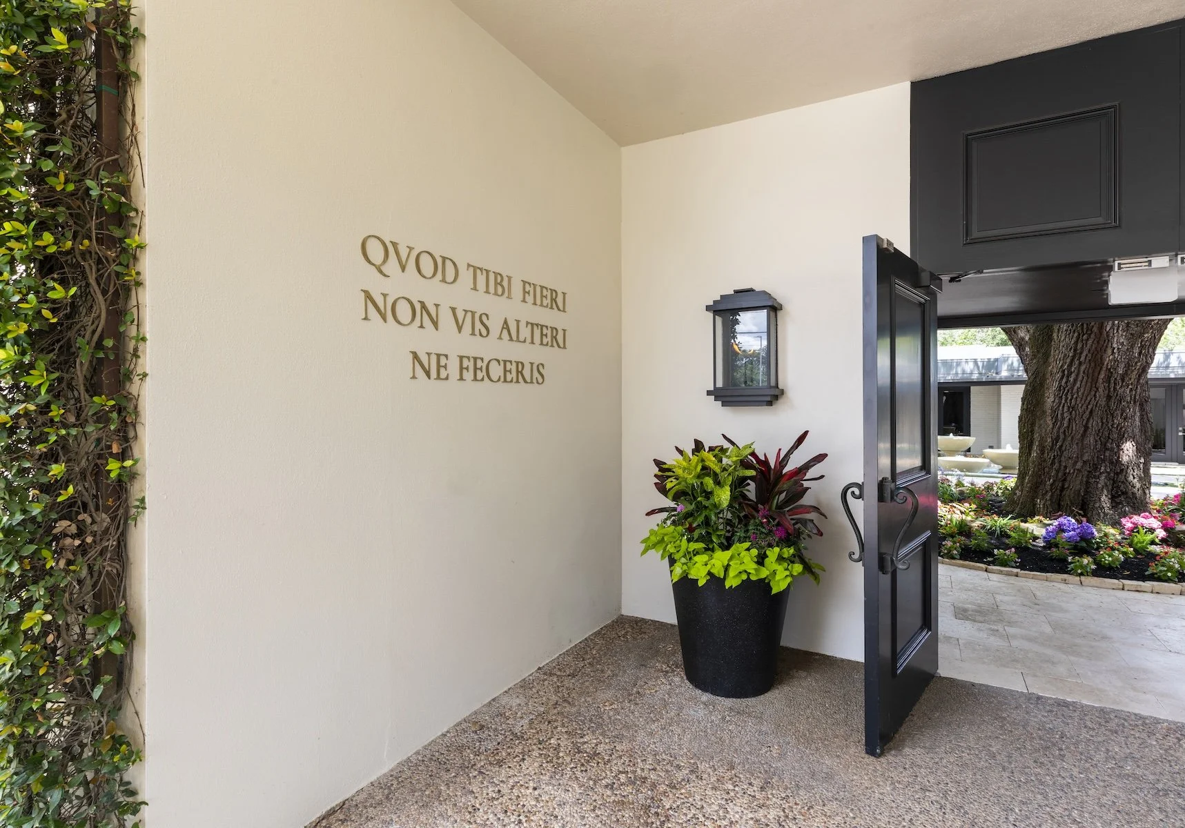 Commercial interior design Houston project in River Oaks with a planted entry, black door and custom wall lettering.