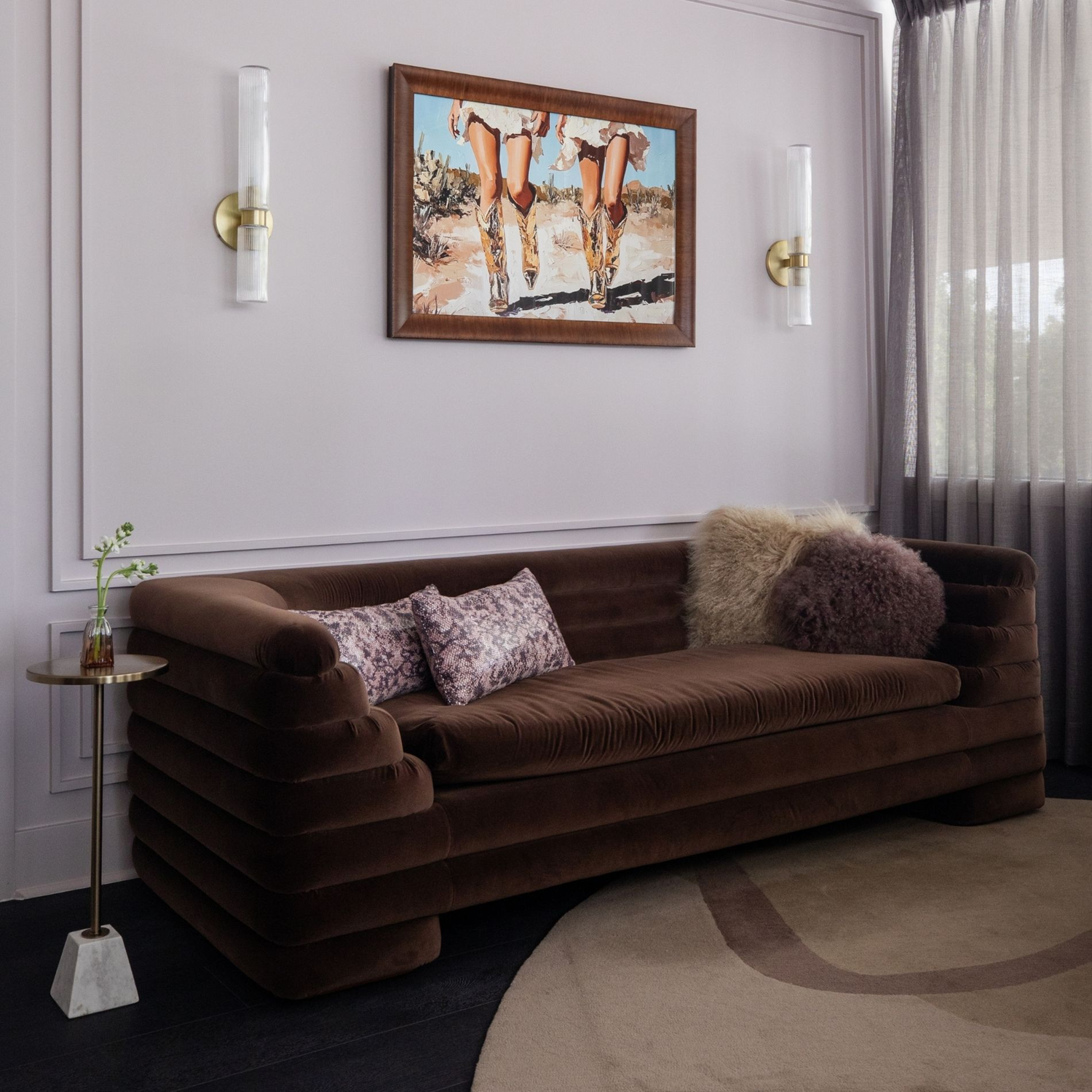 Wellness clinic Houston lounge with a channel-tufted brown velvet sofa, soft sheer curtains and framed Western artwork.