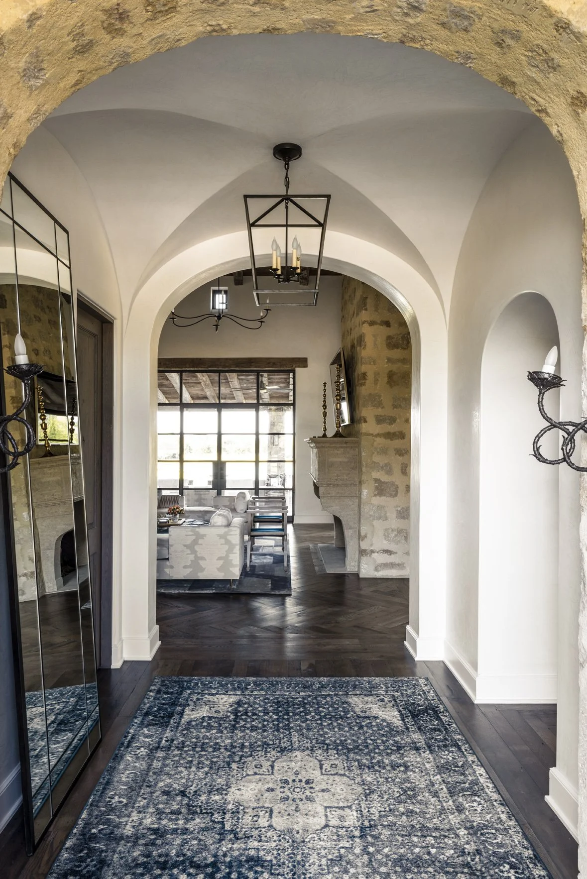 Modern ranch interior design in the Houston Oaks entry hall with arched openings, dark wood floors and a patterned rug.
