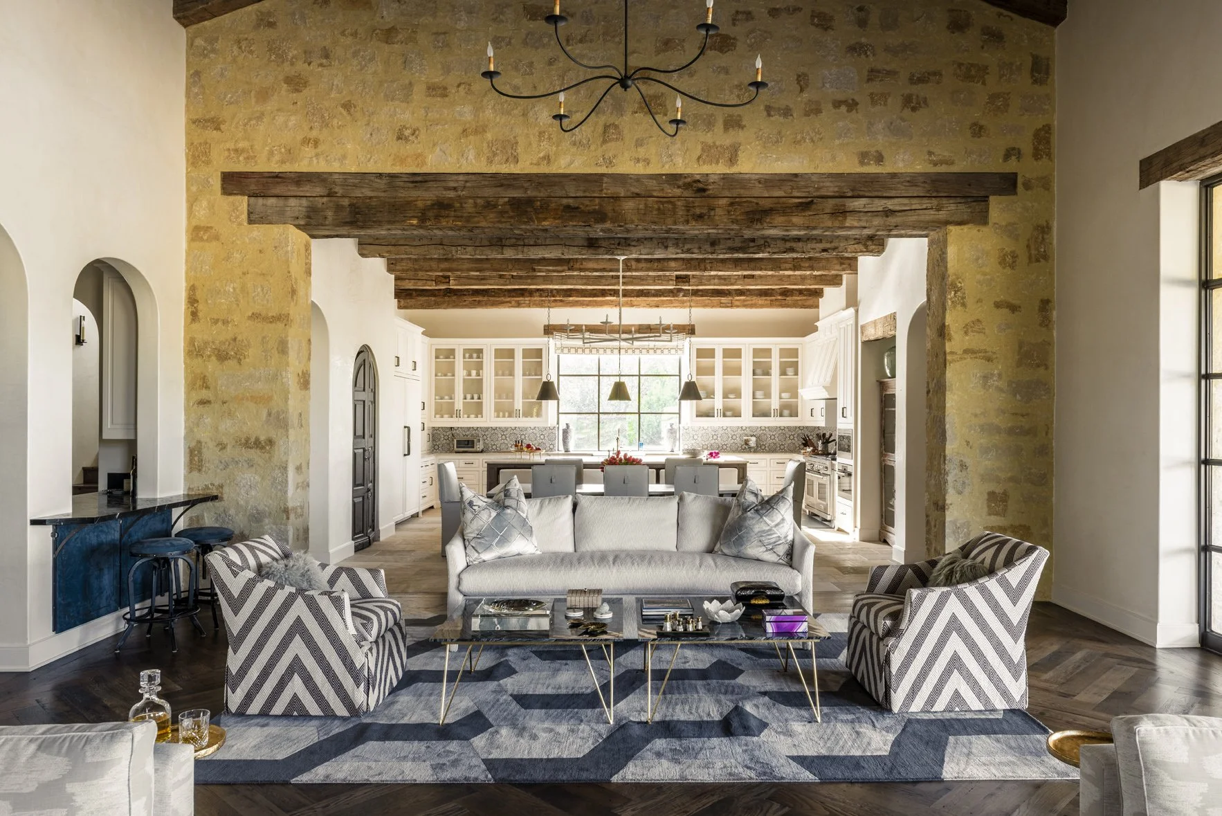 Modern ranch interior design in the Houston Oaks great room, opening to a bright kitchen beneath reclaimed wood beams.
