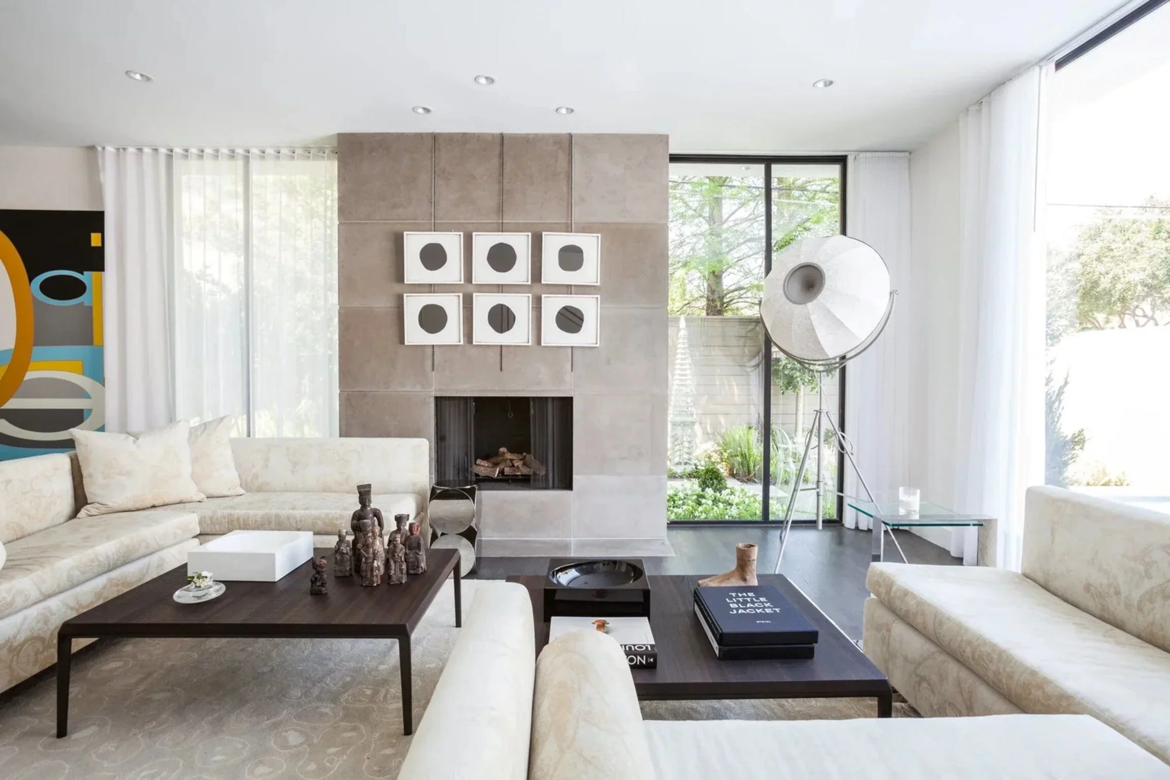 Nuntucker townhome living room with pale upholstered seating, contemporary art, a central fireplace and garden views.