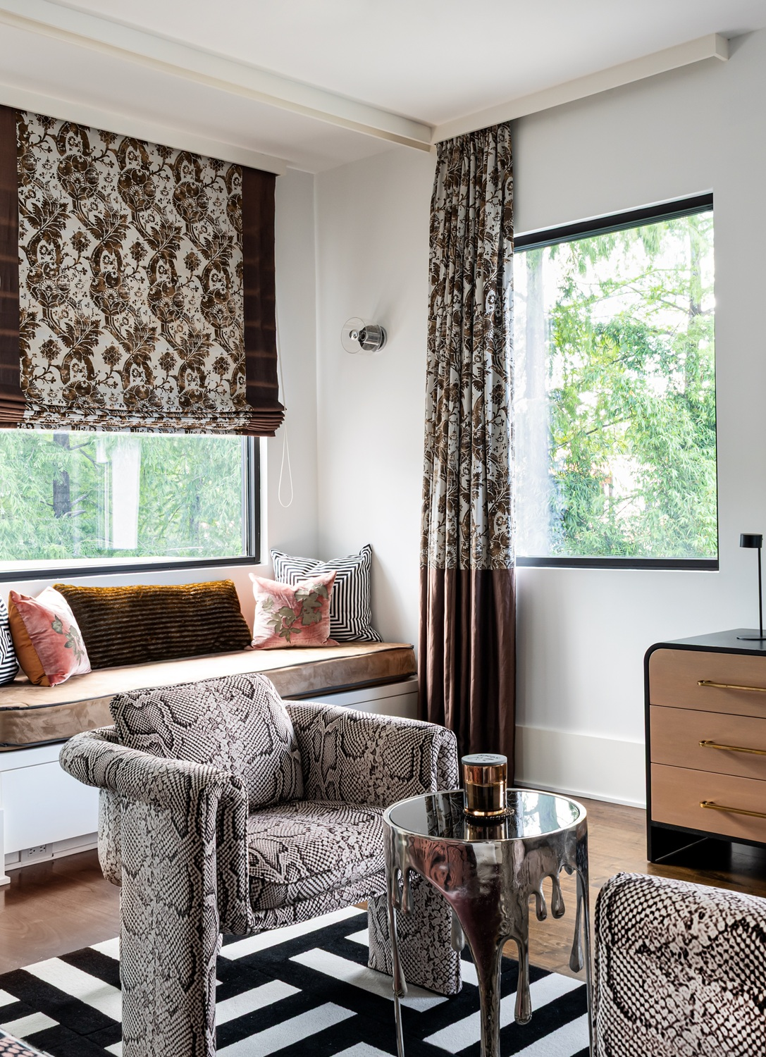Modern luxury home in Houston guest bedroom with a snakeskin chair, metallic side table and upholstered window seat.