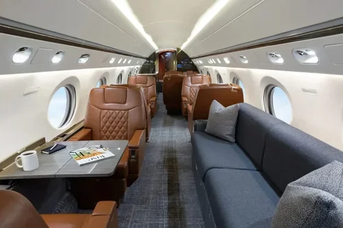 Commercial interior design project for a Gulfstream V business jet, with cognac leather seating, gray sofa and worktable.