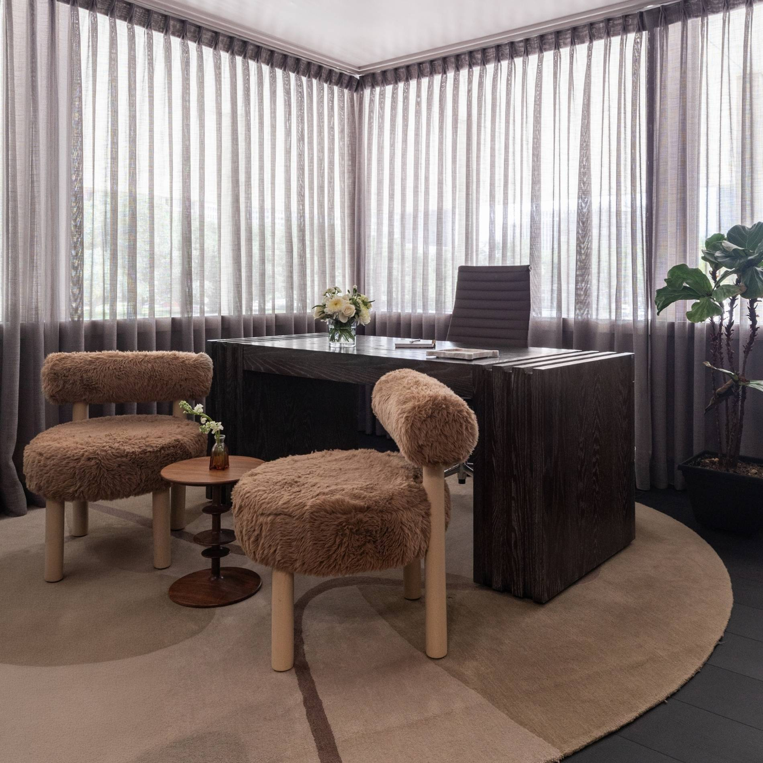 Wellness clinic Houston consultation room with a dark wood desk, plush guest chairs and floor-to-ceiling sheer curtains.