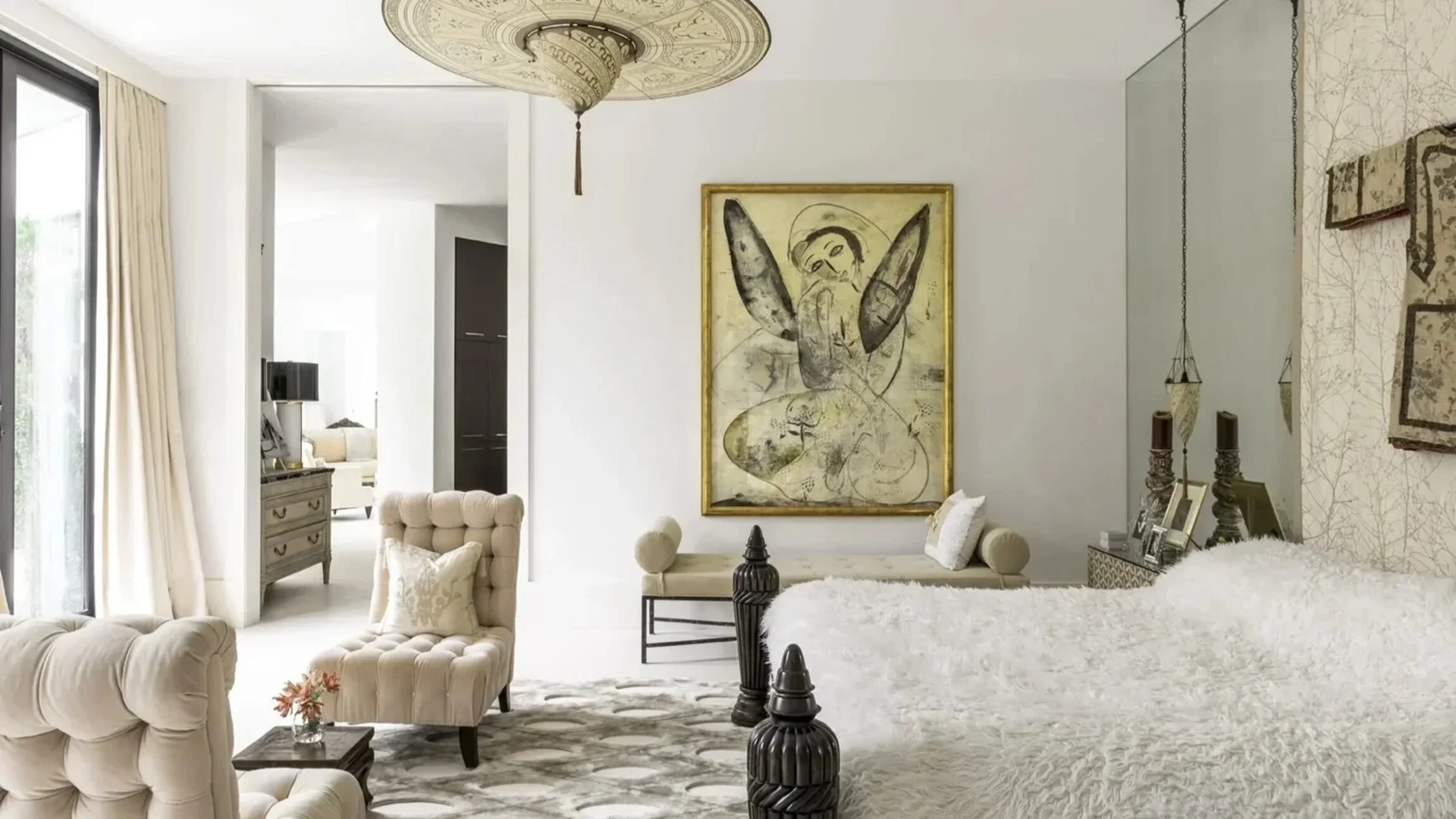 Saddlebranch residence bedroom with tufted seating, a white textured bed and layered neutral artwork.