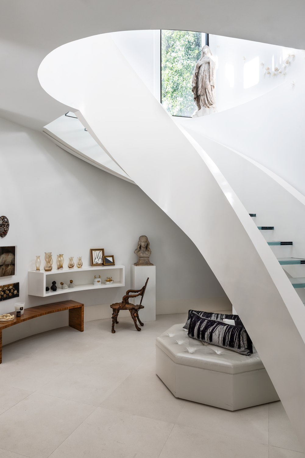 Modern luxury home in Houston with a sweeping white staircase, floating glass treads, sculptures and display shelving.