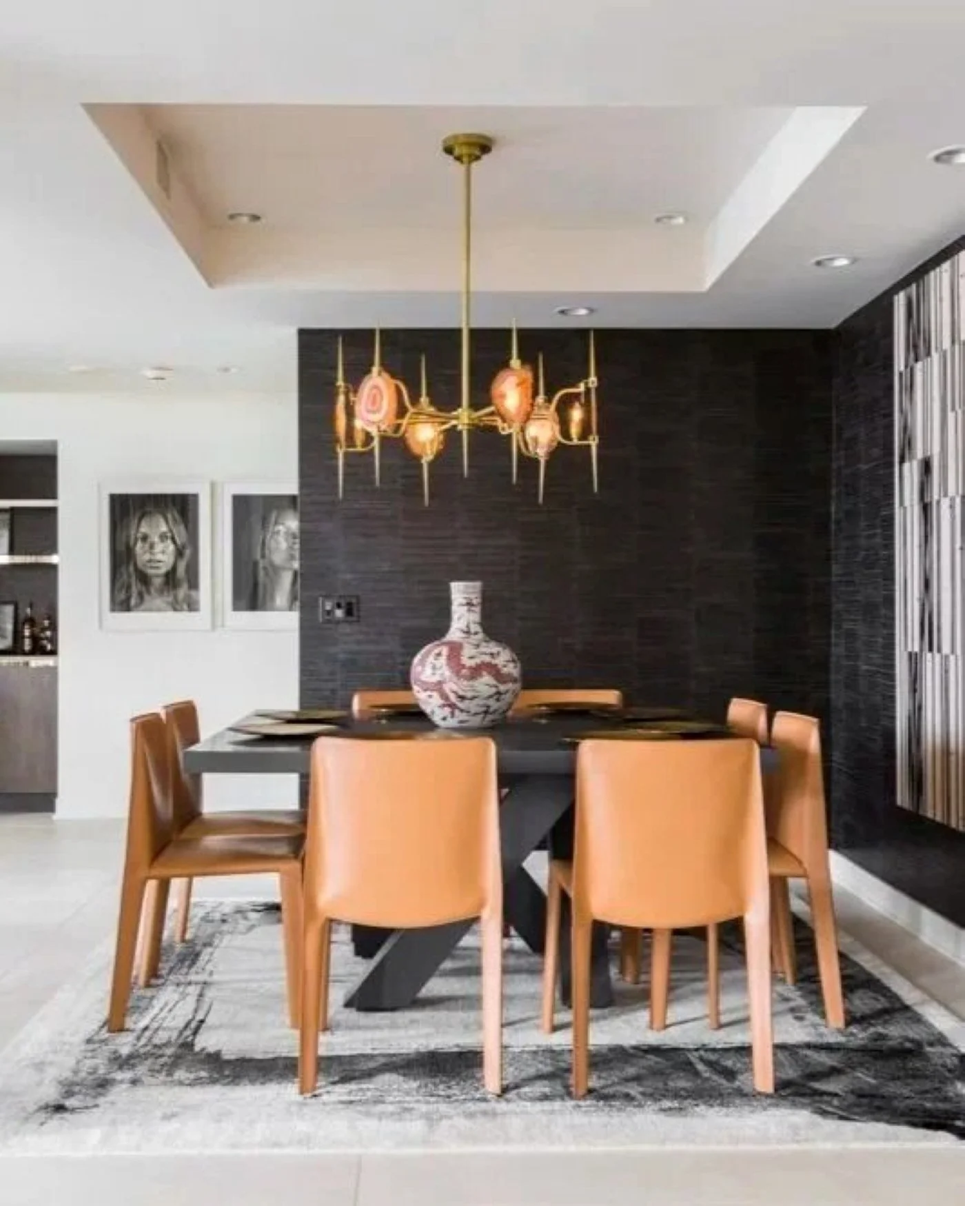 Greenway residence dining room with tan leather chairs, a dark feature wall and sculptural pendant lighting.