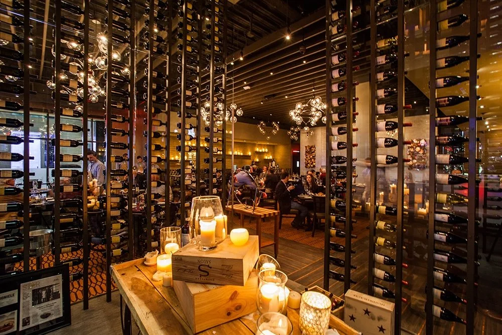 Commercial interior design Houston restaurant at Vallones, with floor-to-ceiling wine storage and candlelit dining.