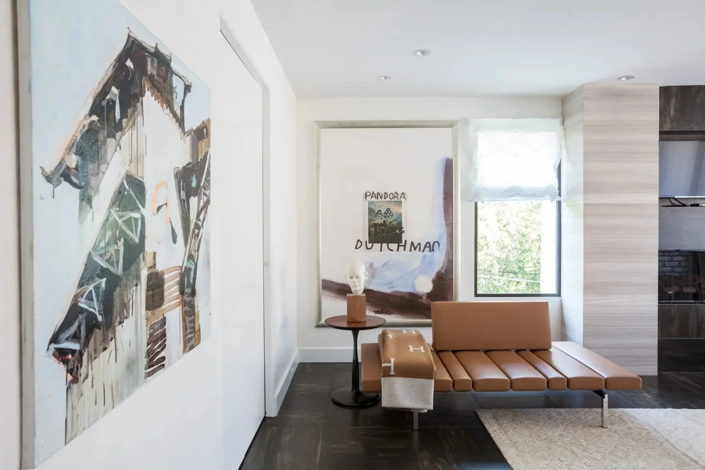 Contemporary sitting area in the Nuntucker townhome with tan leather seating, dark flooring and large-scale artwork.