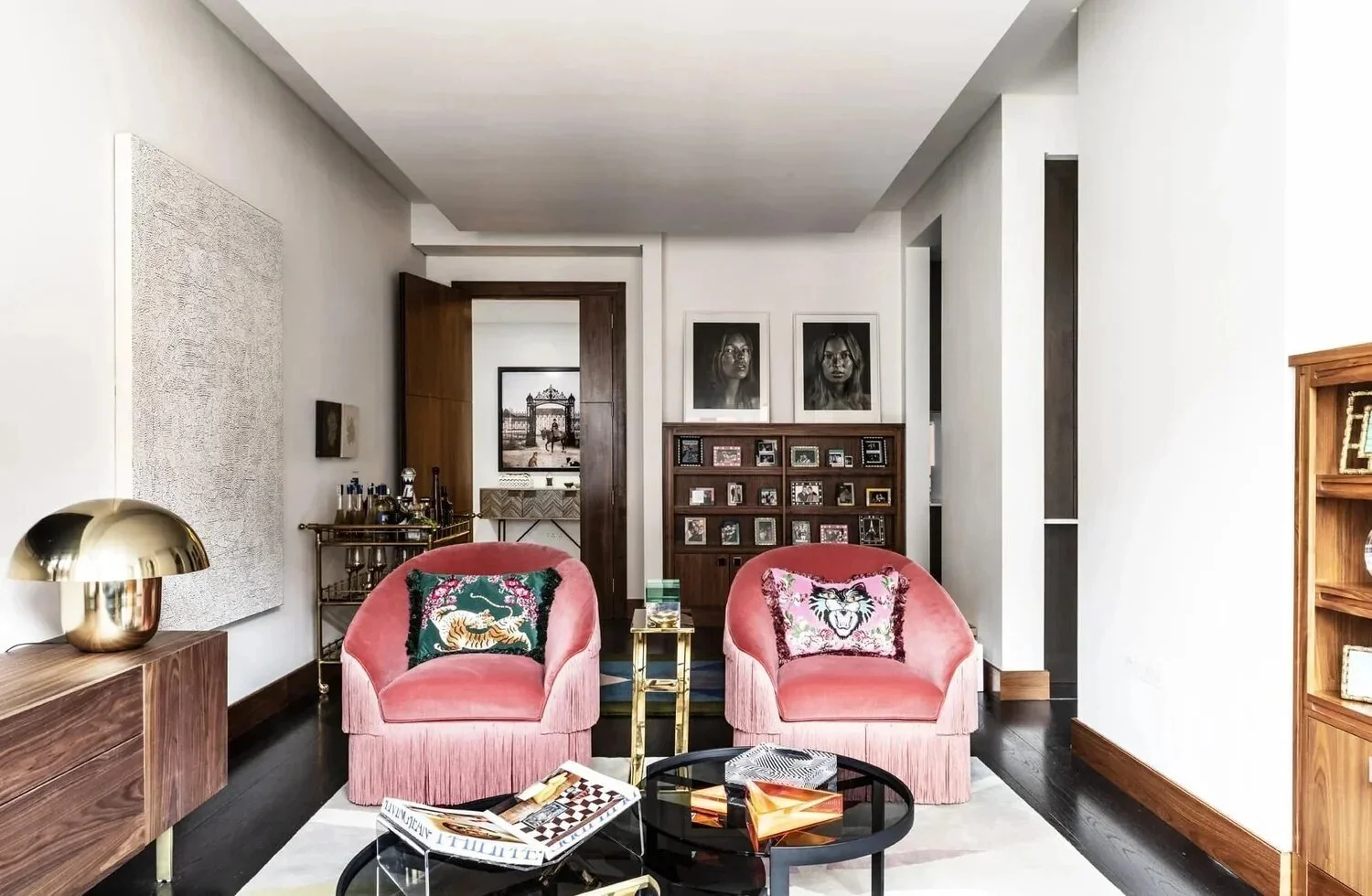 Mayfair London apartment sitting area with pink fringed chairs, walnut cabinetry and curated artwork.
