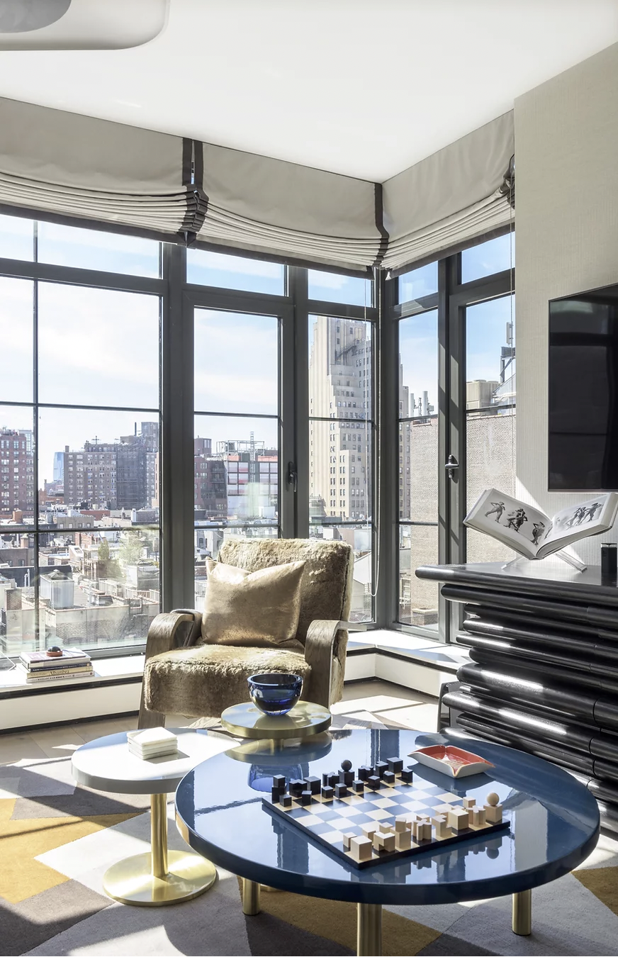 Tribeca interior with panoramic New York views, sculptural furniture, a glossy blue table and custom window treatments.