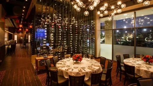 Commercial interior design project at Vallone's restaurant, with wine displays, globe pendants and formal dining tables.