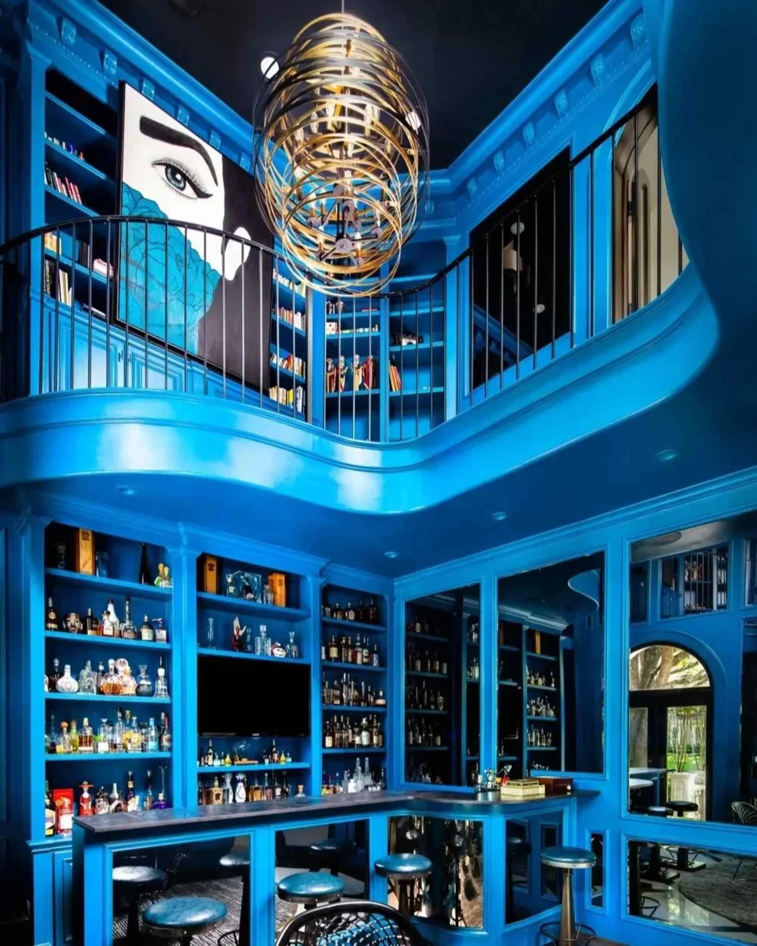Dramatic blue home bar at the Saddlecreek residence with double-height cabinetry, mirrored walls and sculptural lighting.