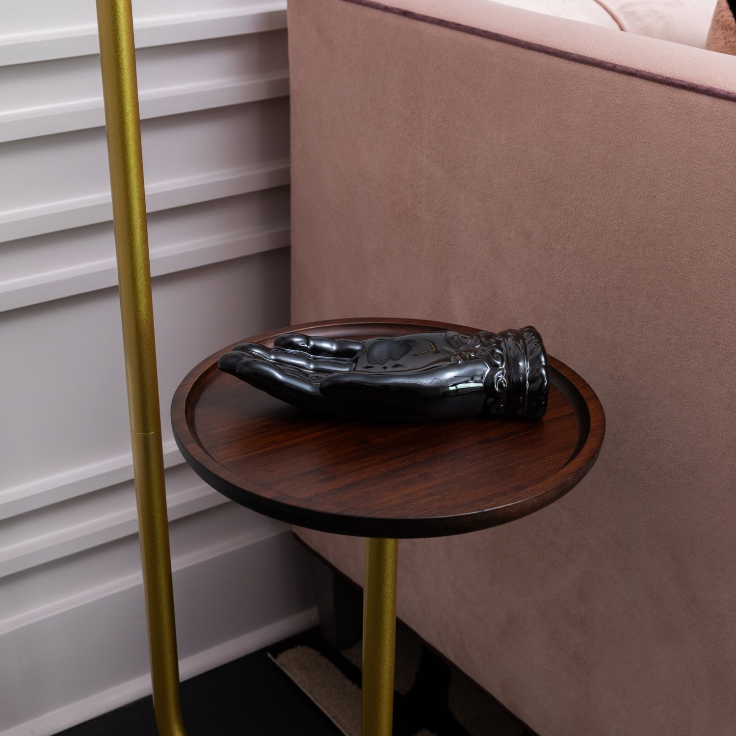 Wellness clinic Houston detail of a black hand sculpture on a wood side table beside the blush pink sofa.
