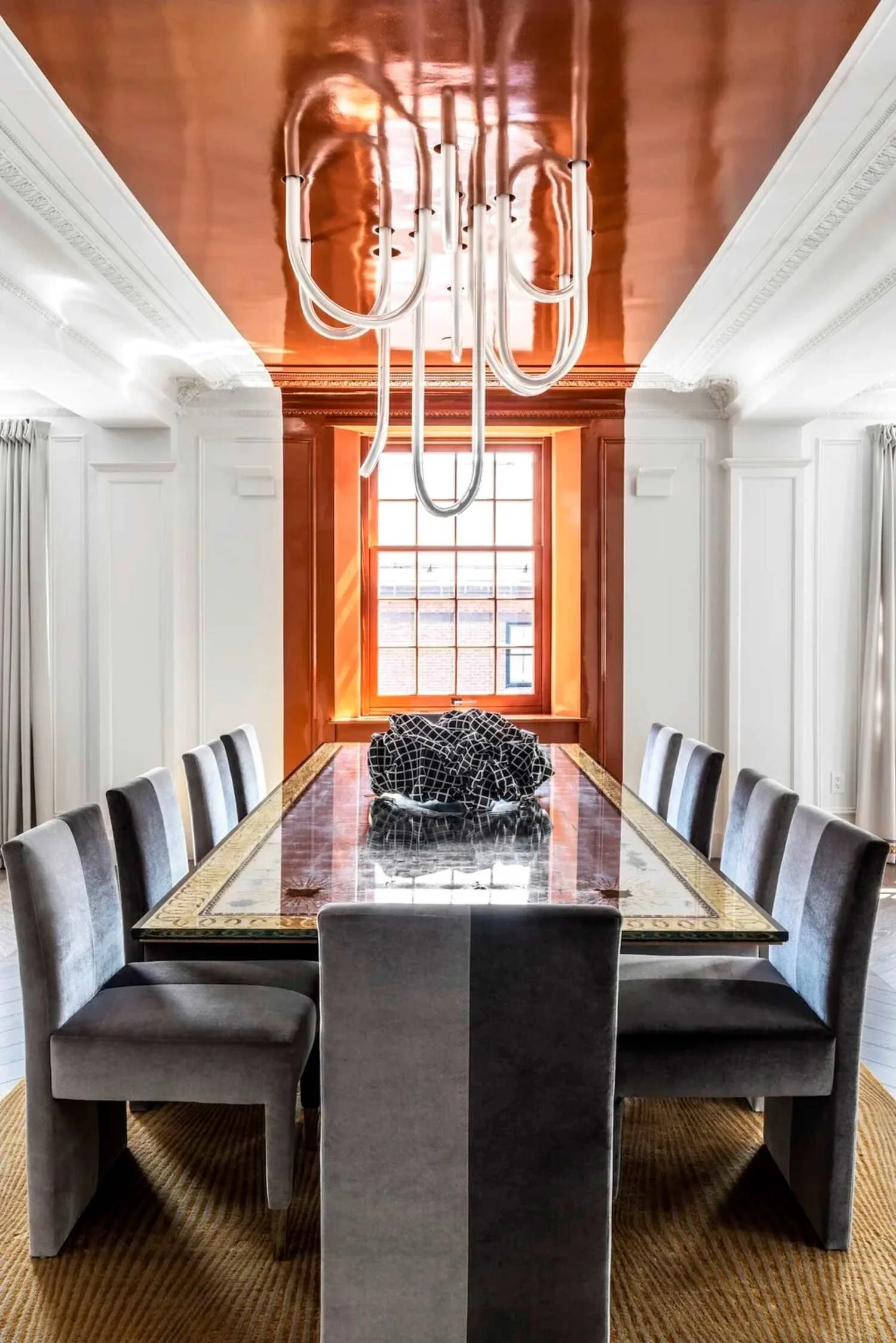 Maison Vernon apartment dining room with a copper ceiling, sculptural chandelier and tailored grey seating.