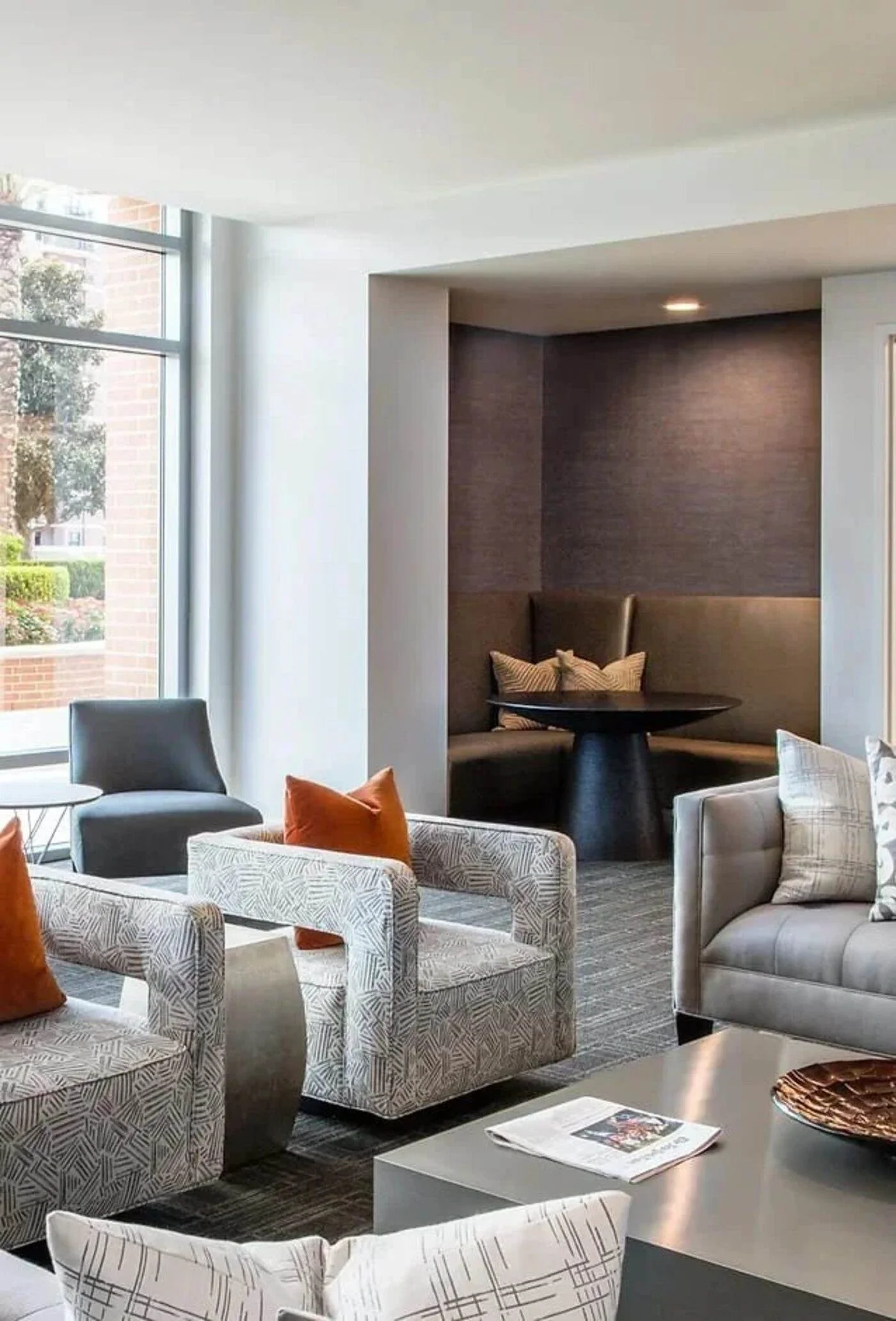 Houston commercial interior design for a multifamily lobby lounge with patterned armchairs, orange accents and private seating.
