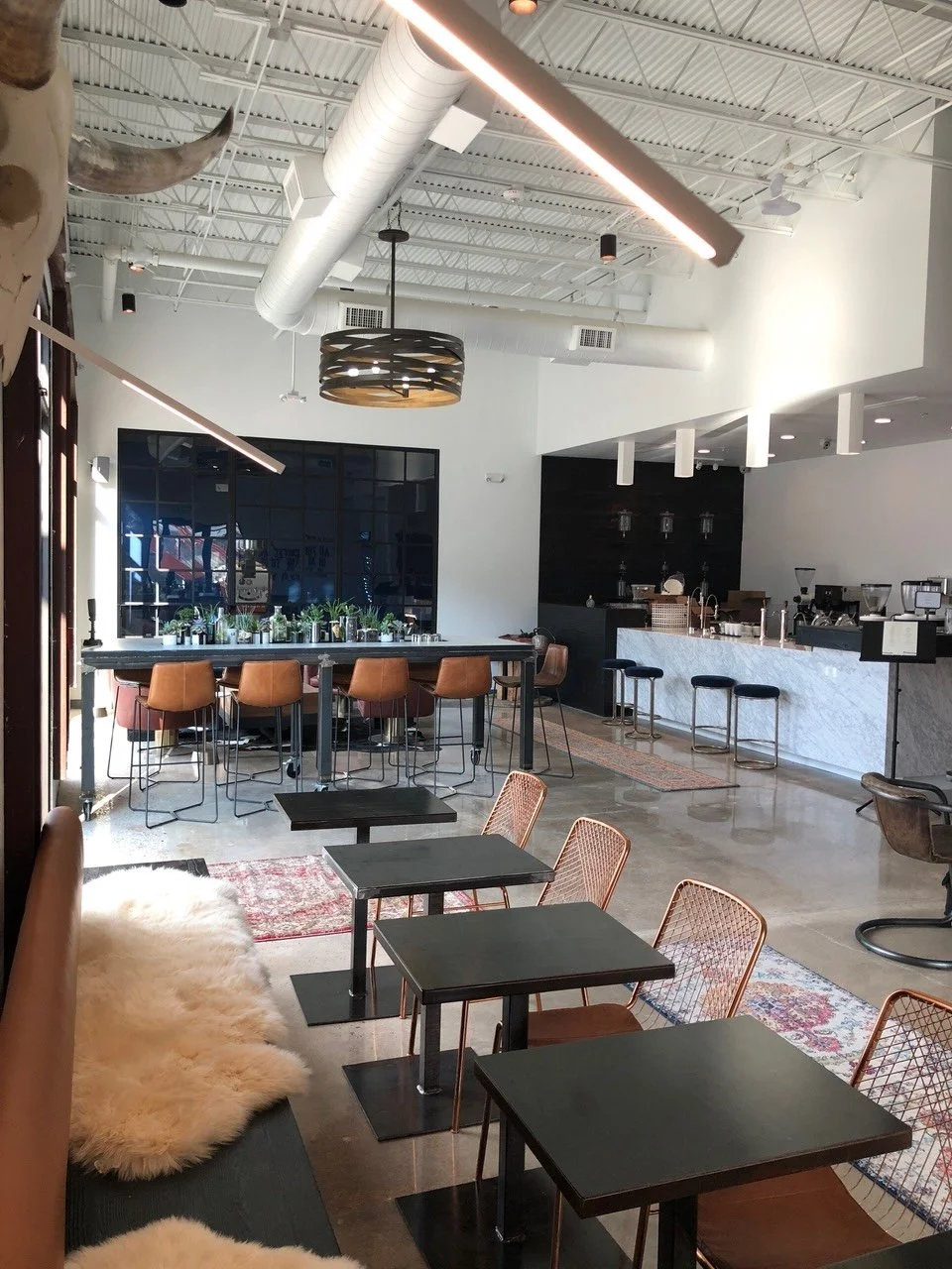 Commercial interior design Houston cafe in Rice Village with leather seating, patterned rugs and a marble service bar.