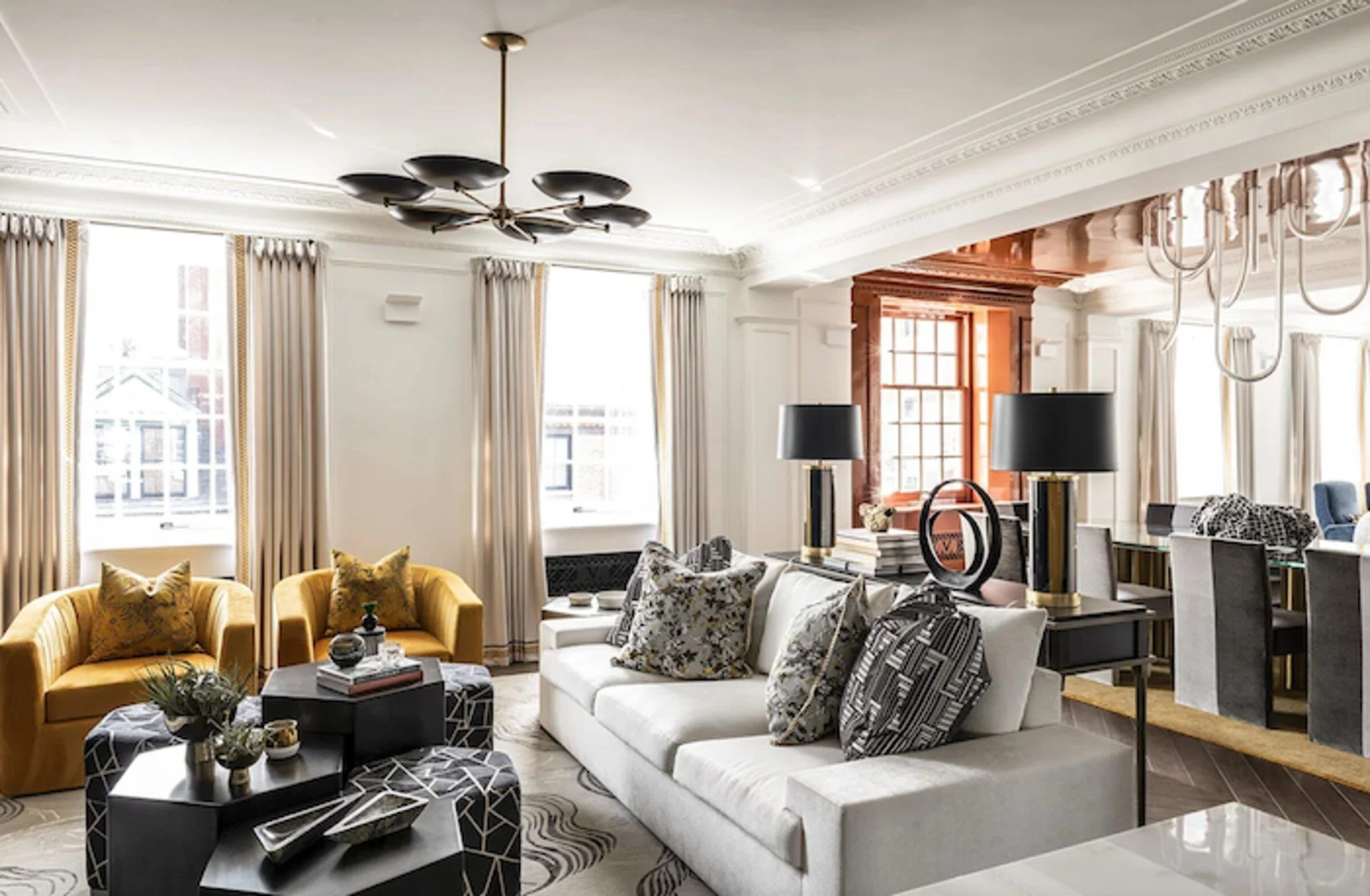 Maison Vernon apartment living room with yellow armchairs, patterned furnishings and layered contemporary lighting.