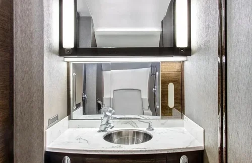 Commercial interior design project for a Falcon 2000 private jet, with marble vanity and dark wood cabinetry.