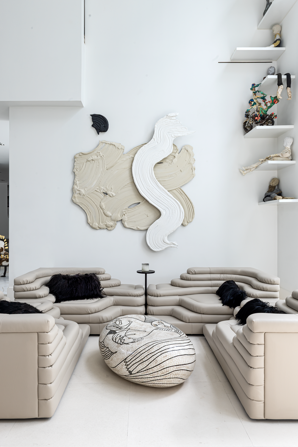 Modern luxury home in Houston living area with sculptural cream sofas, black fur cushions and large-scale wall art.