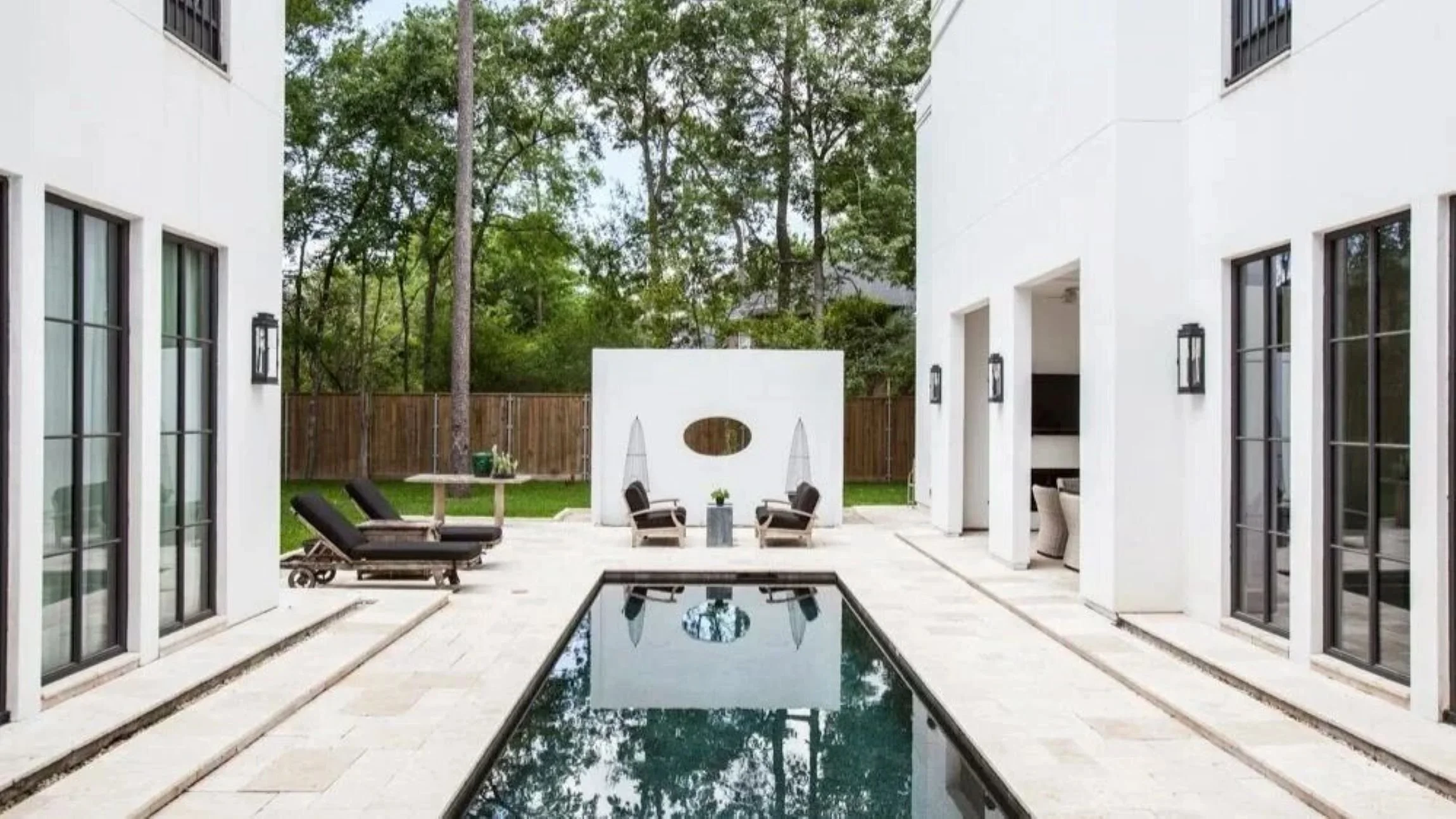 Bunker Hill II residence pool courtyard framed by white façades, black windows, outdoor seating and sun loungers.