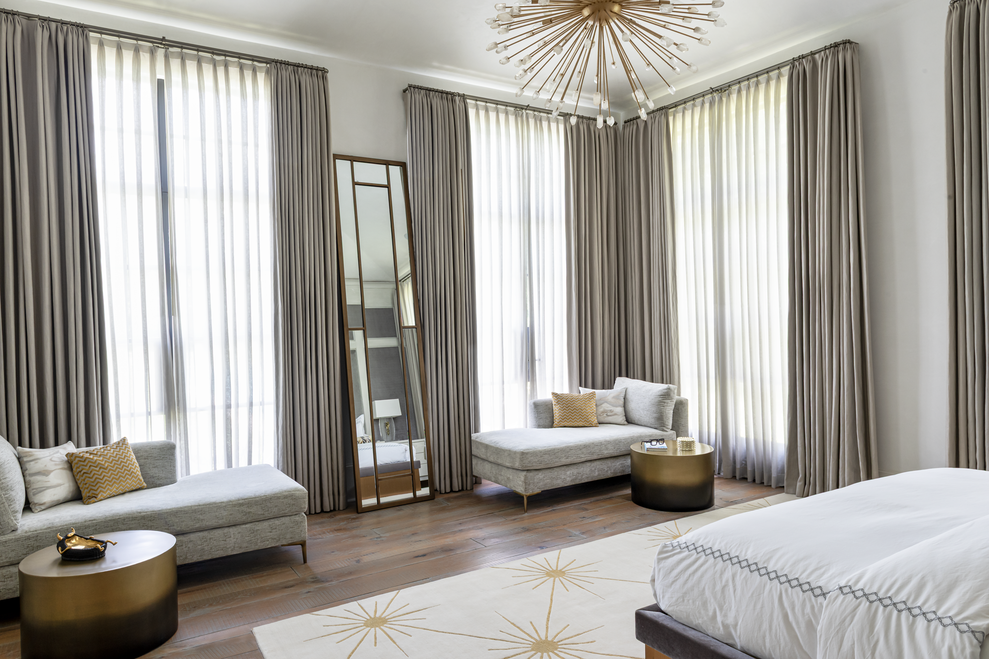 French country home in Houston primary bedroom with twin chaises, floor-to-ceiling drapery and a brass starburst chandelier.