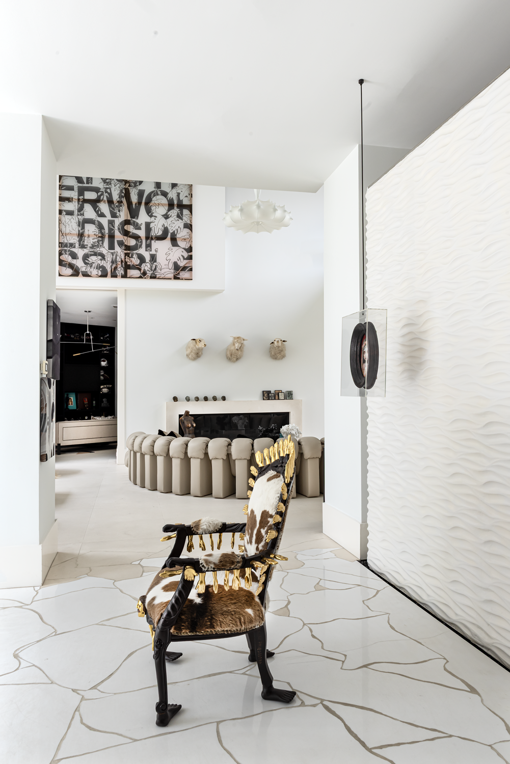 Modern luxury home in Houston entry with a collectible sculptural chair, textured feature wall and art-filled living room.