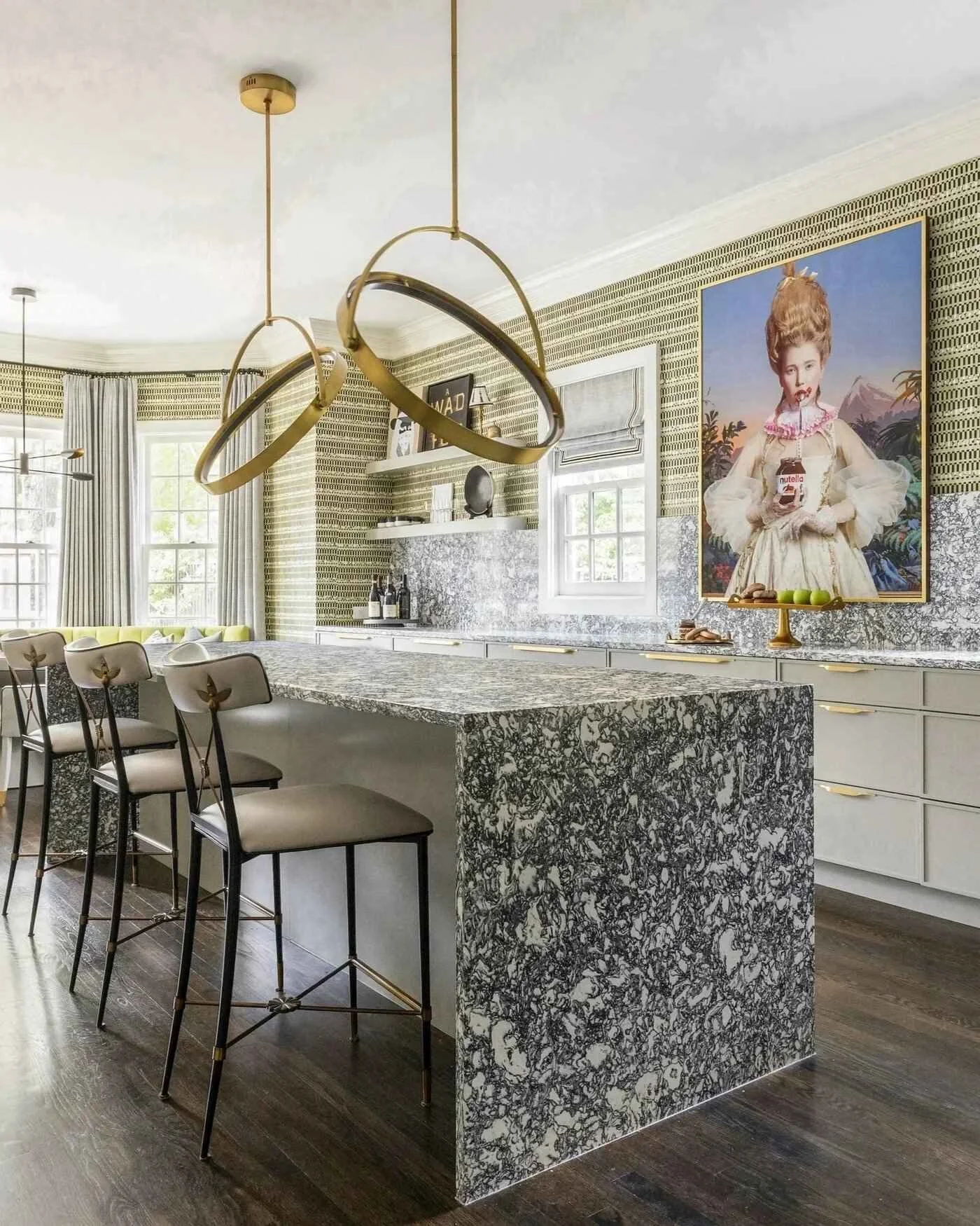 Bunker Hill residence kitchen with a patterned stone island, brass lighting, grey cabinetry and statement portrait artwork.