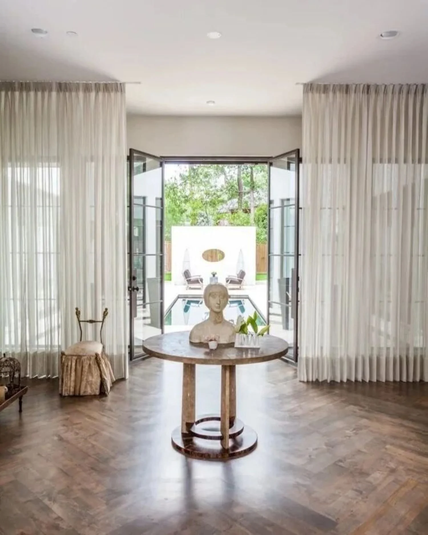 Bunker Hill II residence entry hall with herringbone flooring, a sculptural console and views towards the pool.