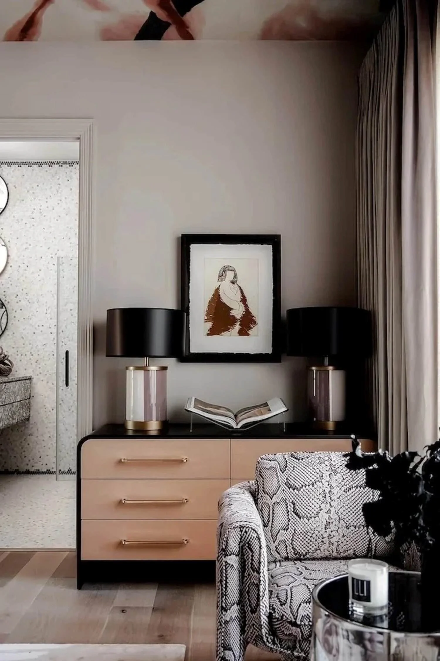 Kips Bay Dallas bedroom sitting area with a snakeskin chair, blush cabinetry, black lamps and curated artwork.