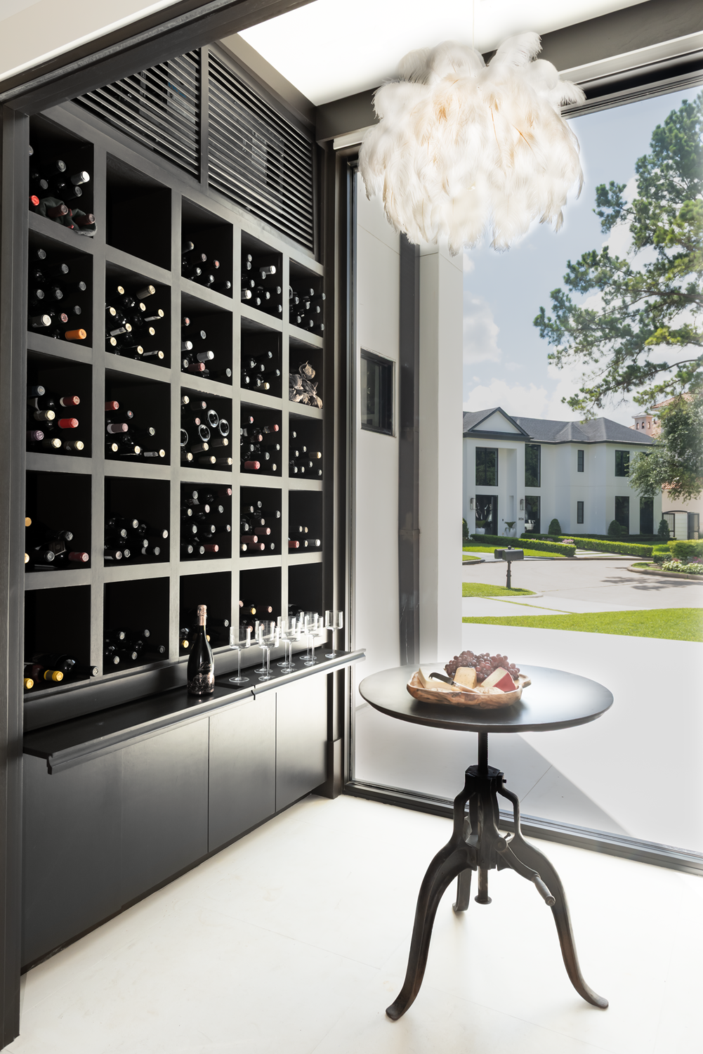 Modern luxury home in Houston with a black wine storage wall, sculptural feather pendant and round tasting table.