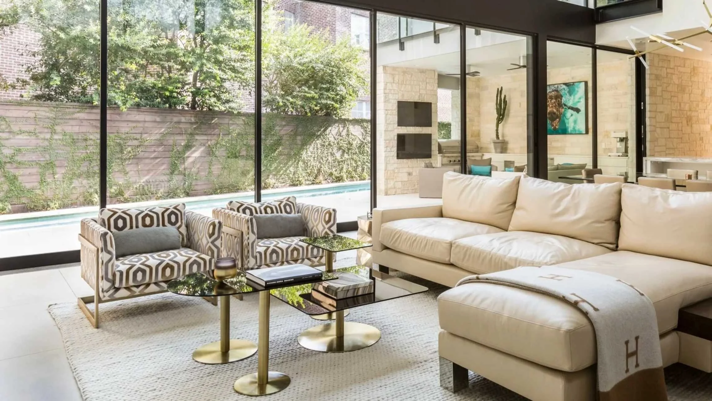 Stanmore residence open-plan living room with white furnishings, geometric armchairs and views towards the outdoor pool.