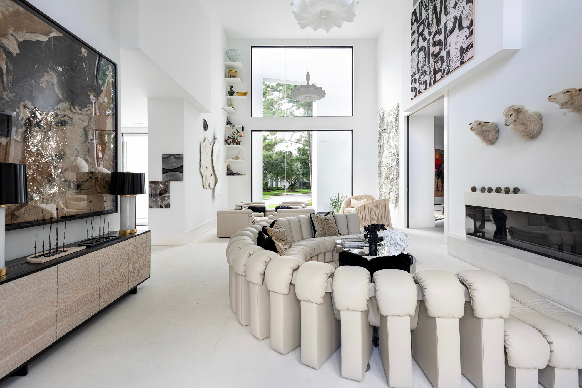 Modern luxury home in Houston living room with a curved De Sede sofa, black fur cushions and large-scale contemporary art.