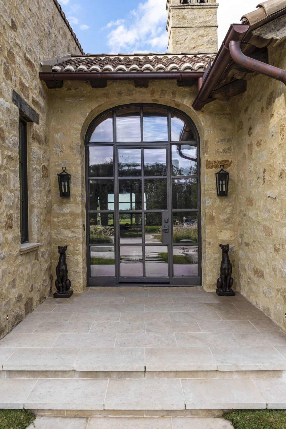 Arched steel-framed entry door set within the stone exterior of the modern Texas ranch at Houston Oaks.