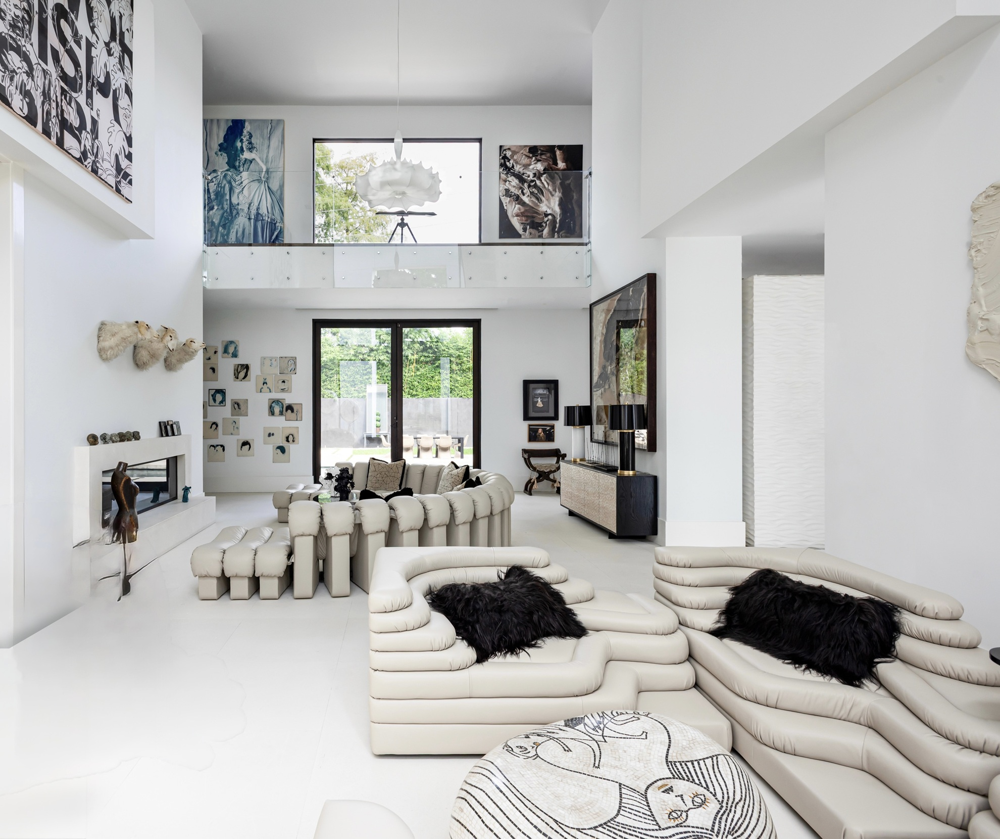Modern luxury home in Houston double-height living room with sculptural cream seating, contemporary art and glass balcony.