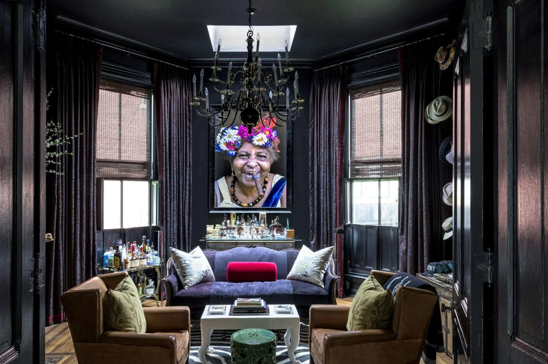 Dark sitting room in the Cherokee Italianate mansion with a crystal chandelier, purple sofa and expressive portrait artwork.