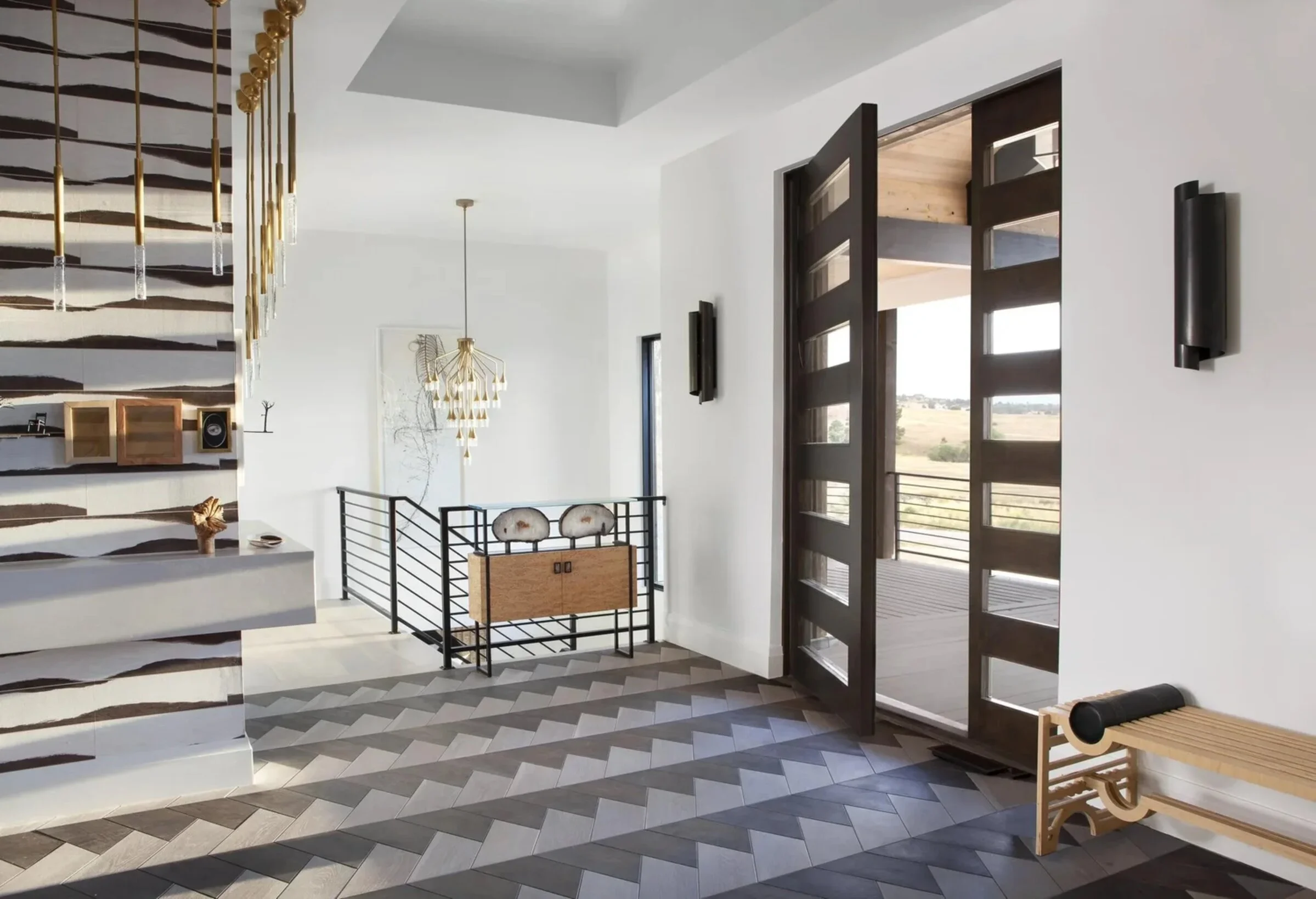 Entry hall of the House Beautiful Colorado residence, with graphic wallcovering, brass pendants and chevron flooring.