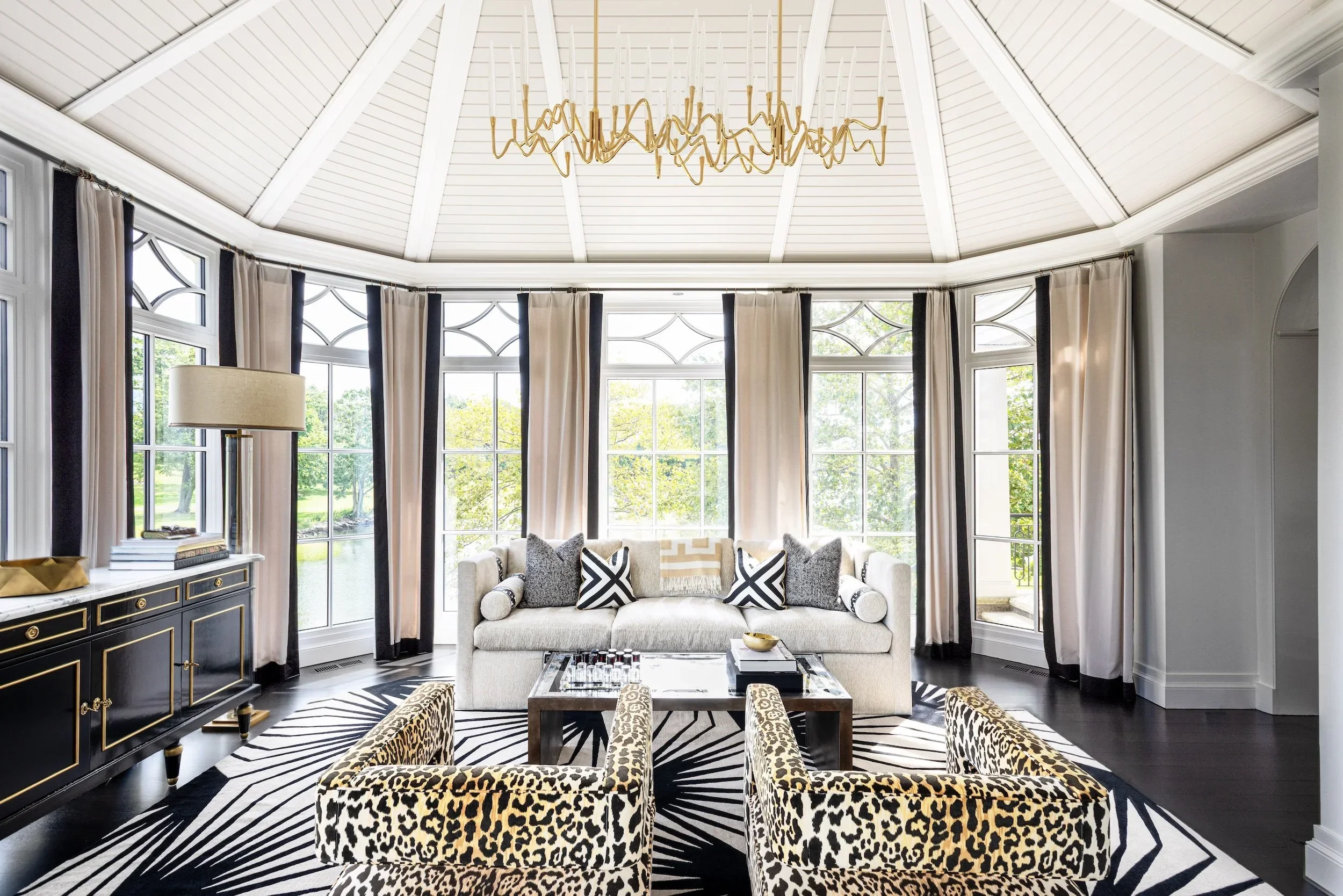 Luxury residential interior design sunroom with panoramic windows, statement patterned seating, and a bright tailored entertaining space