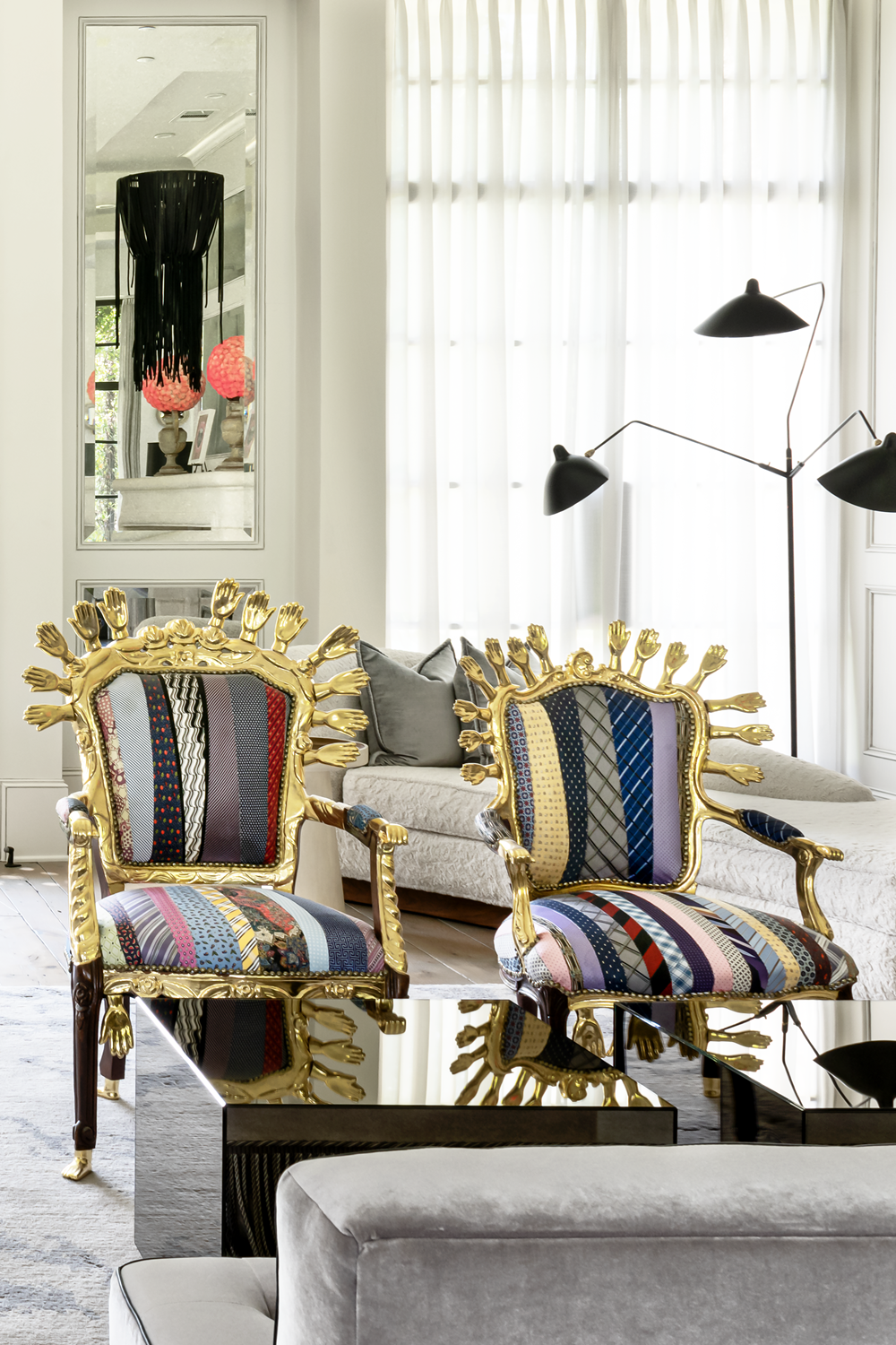 French country home in Houston living room with ornate gold hand chairs, patchwork upholstery and sculptural lighting.