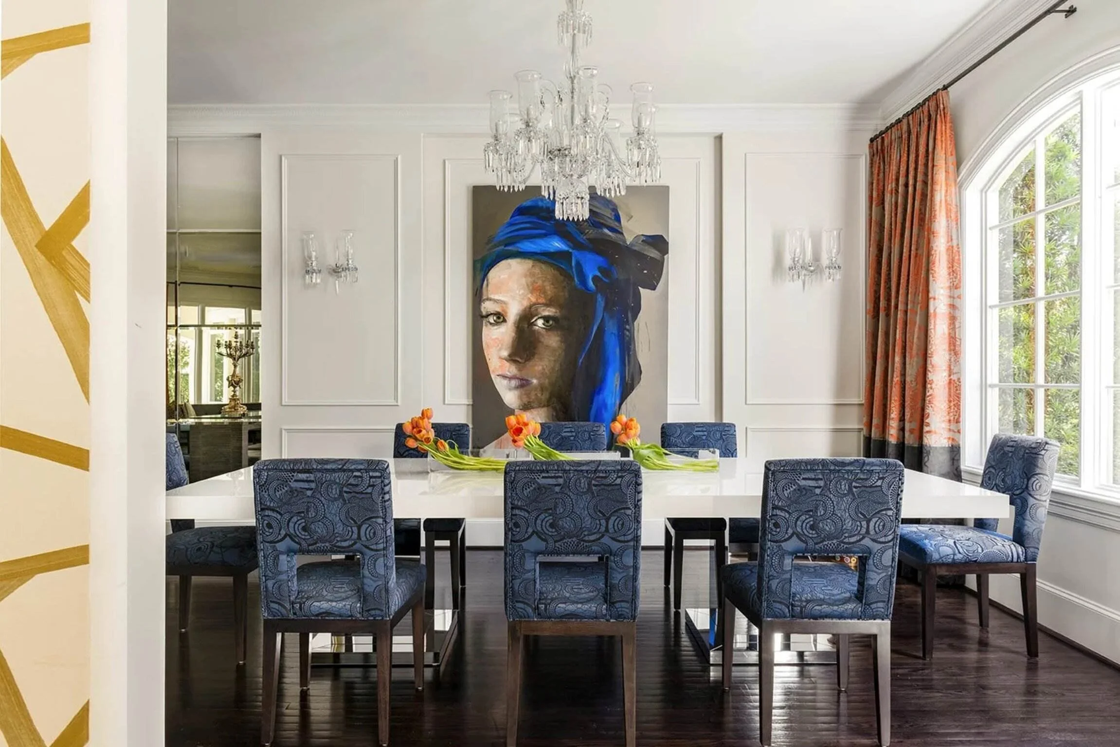 Saddlebranch II residence dining room with blue patterned chairs, crystal chandelier and large portrait artwork.